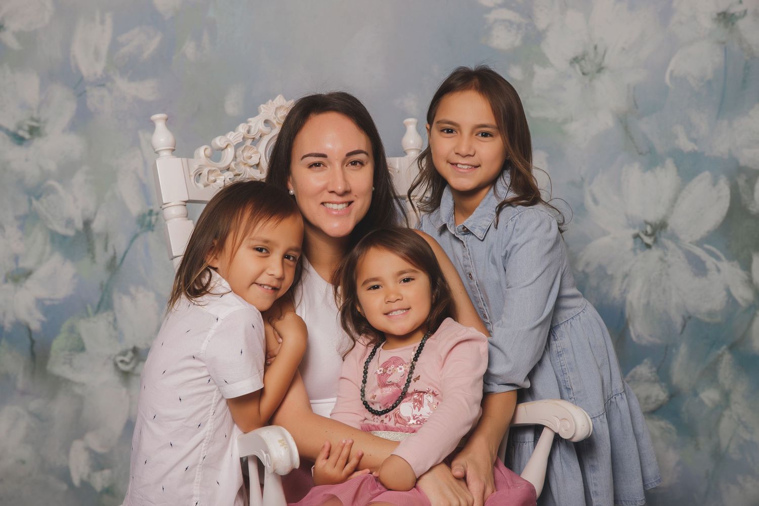 Portrait of a group of people posing together and smiling against a floral backdrop.