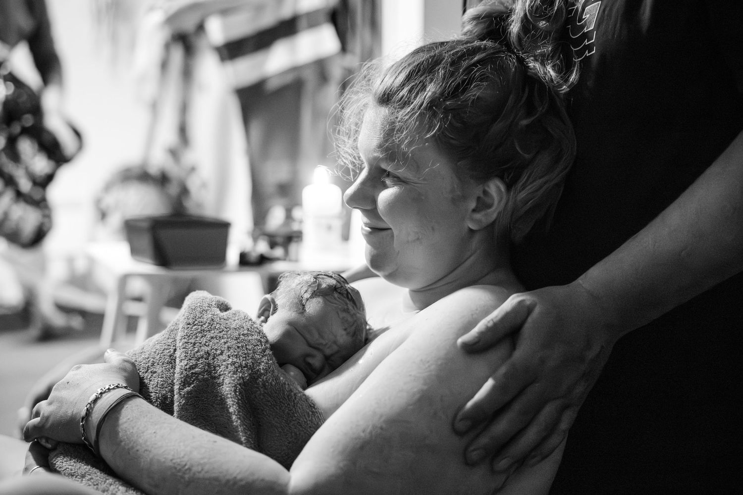 Black and white image showing a tender moment during labor and delivery with a person holding a teddy bear in a hospital setting.