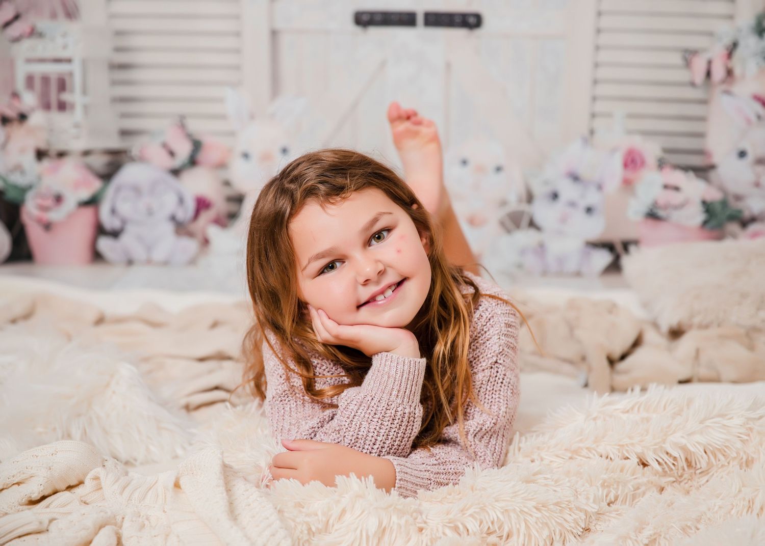 Professional photo shoot setup with white bedding and floral decor in soft pink tones.