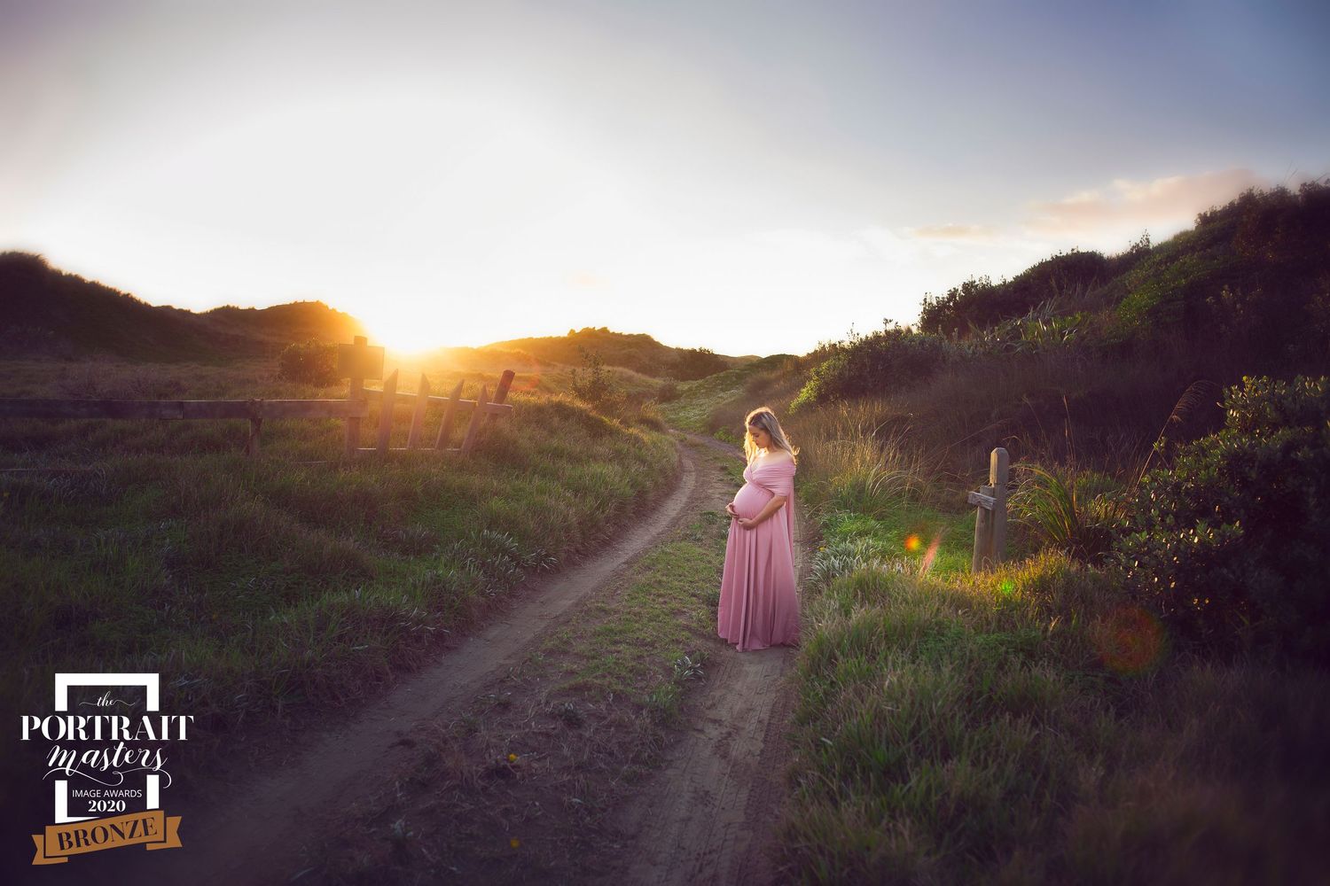 Purple dress flowing in the wind against golden sunset on mountain path creates ethereal silhouette.