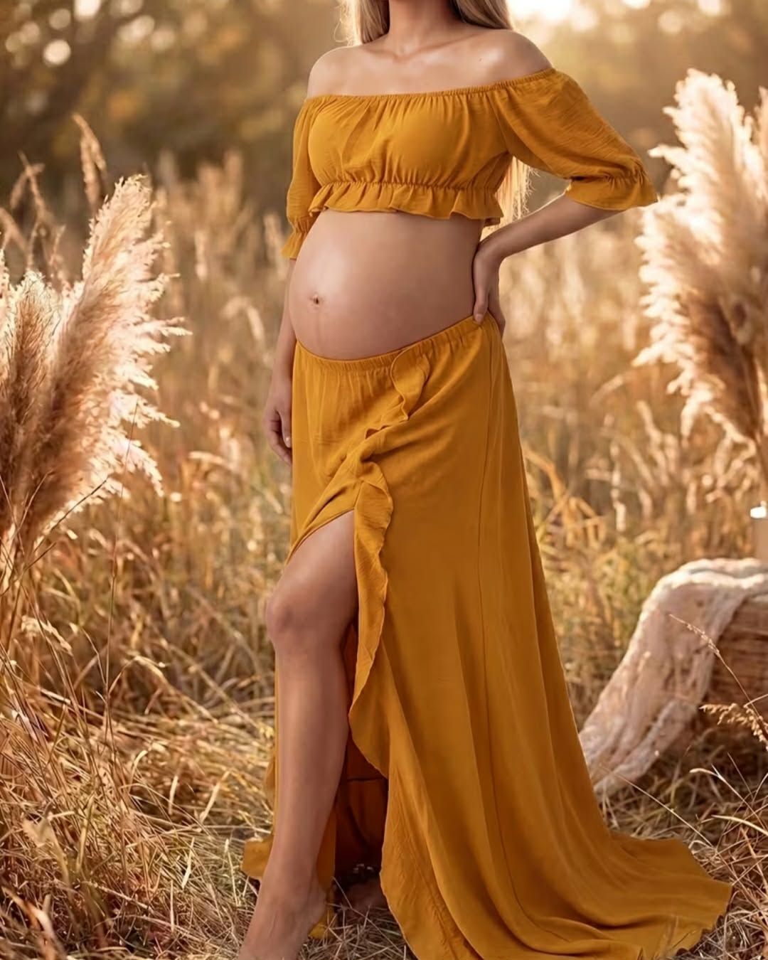 Pregnant woman in mustard yellow off-shoulder crop top and maxi skirt with slit, posing in golden field.