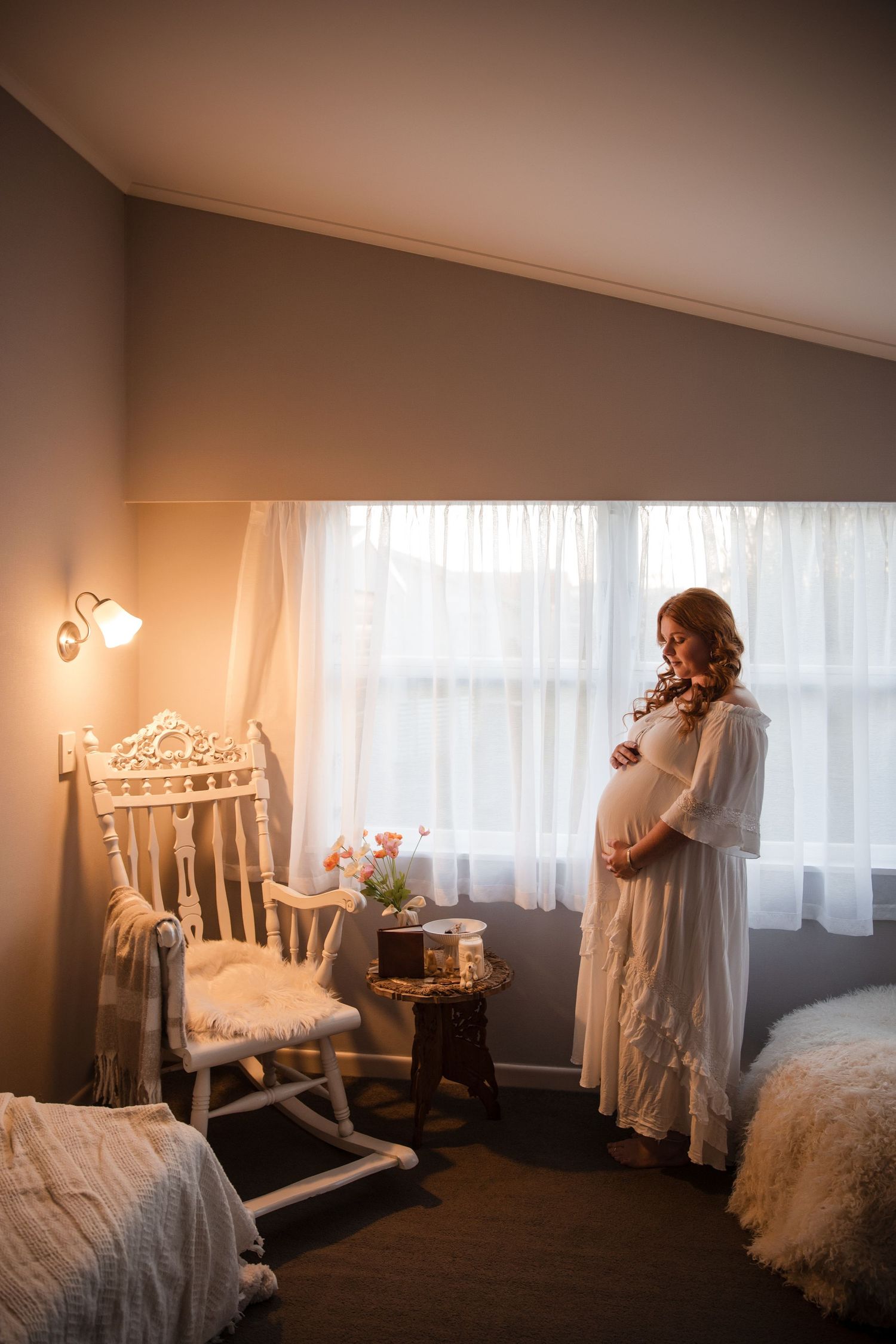 Moody boudoir photo series showing a white vintage bed frame and lace décor in soft natural window lighting.