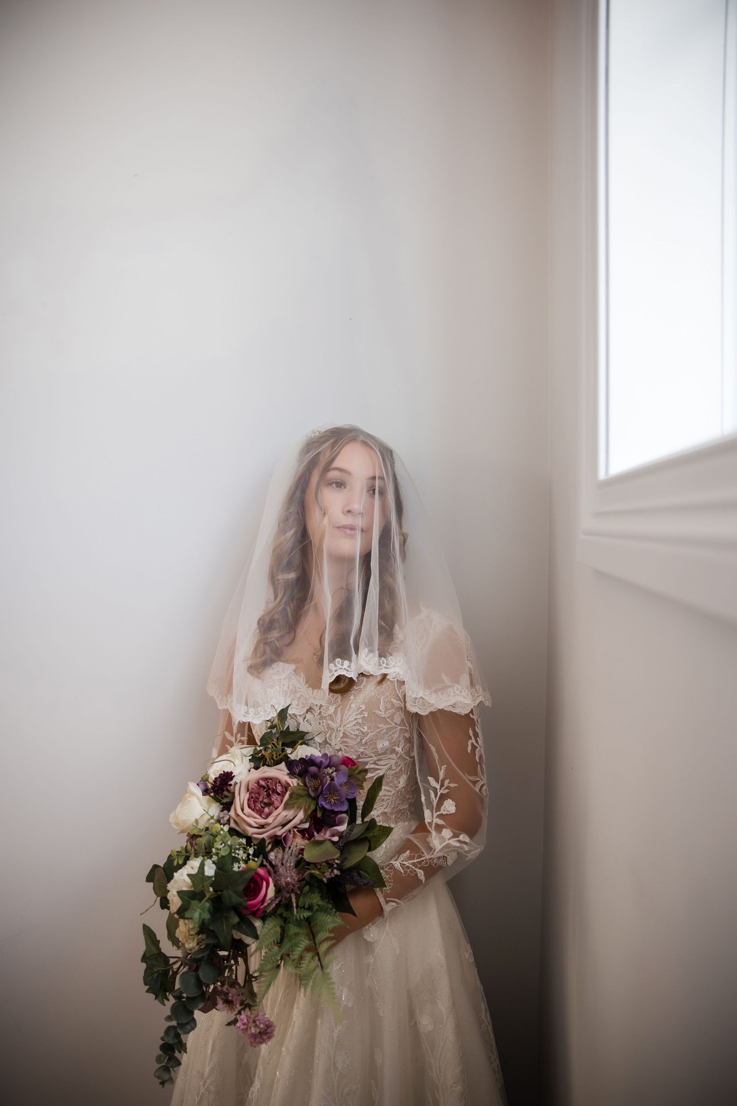 Ethereal bridal portrait series showing dreamy white dress and purple floral bouquet against soft light.