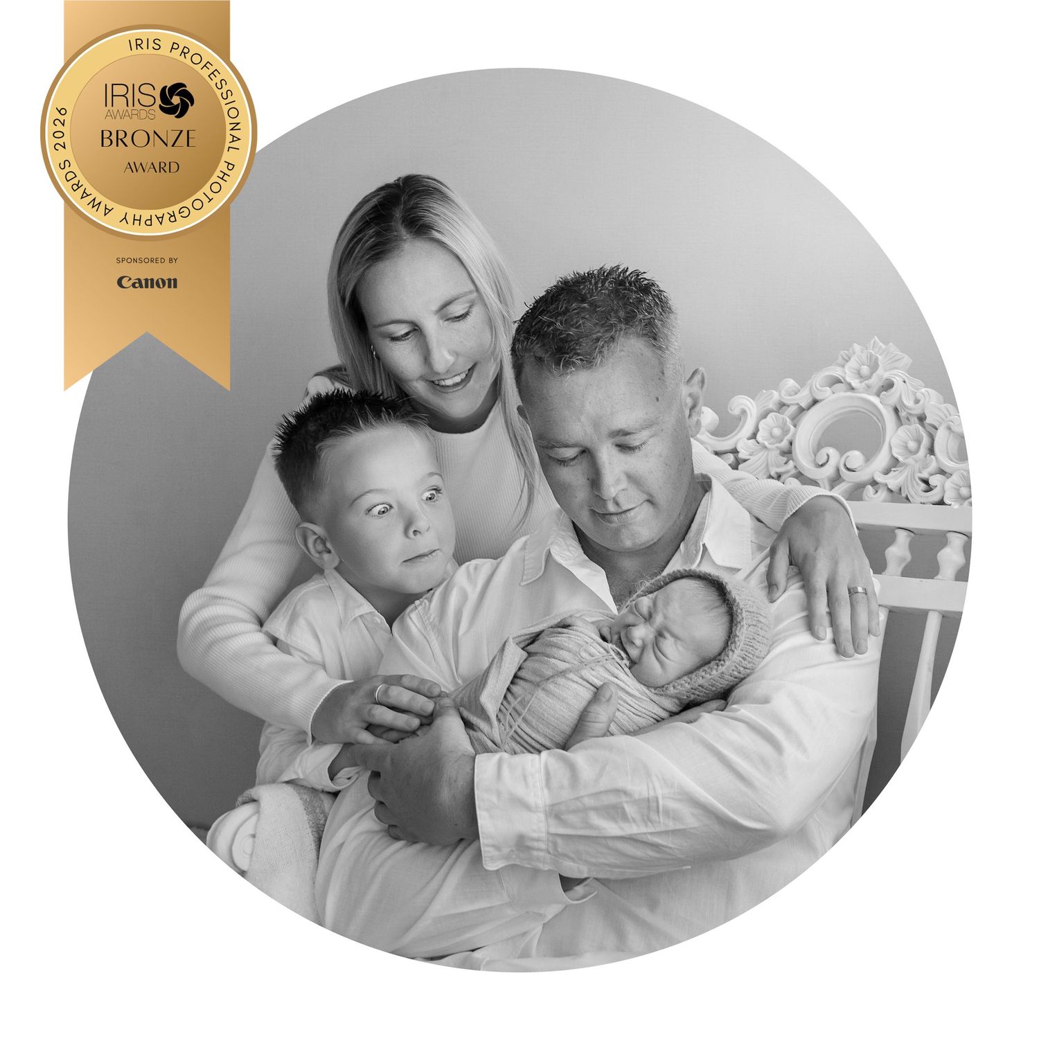 Black and white family portrait of parents with young son and newborn baby, awarded IRIS Bronze Photography Award.