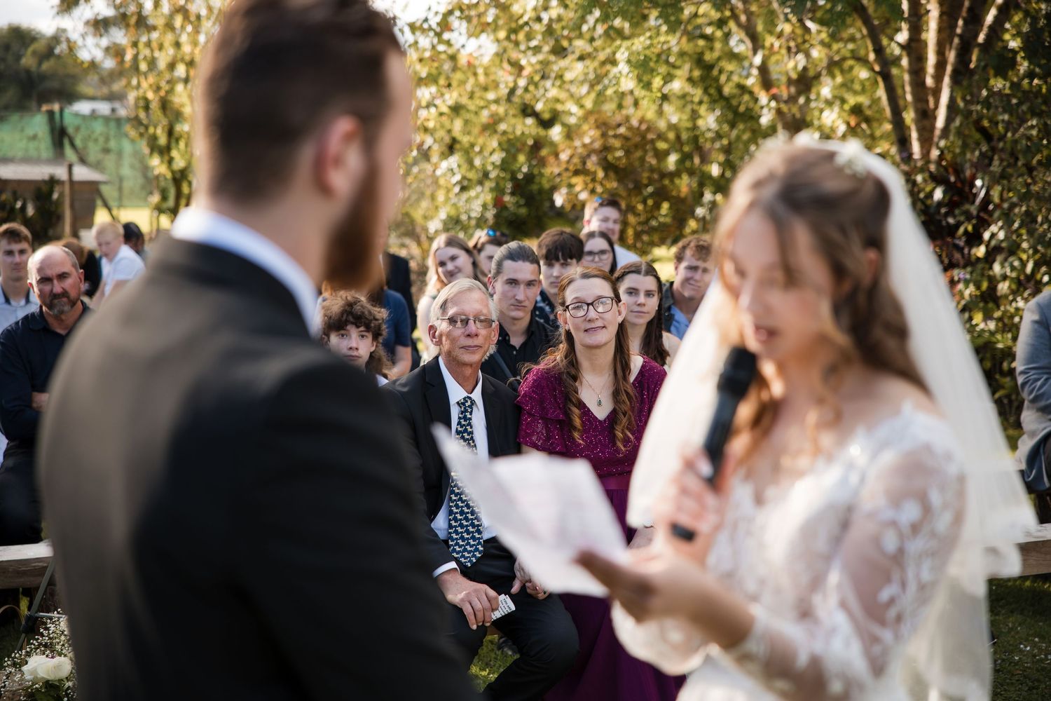 A couple shares a joyful dance at their outdoor wedding ceremony while guests watch and smile.