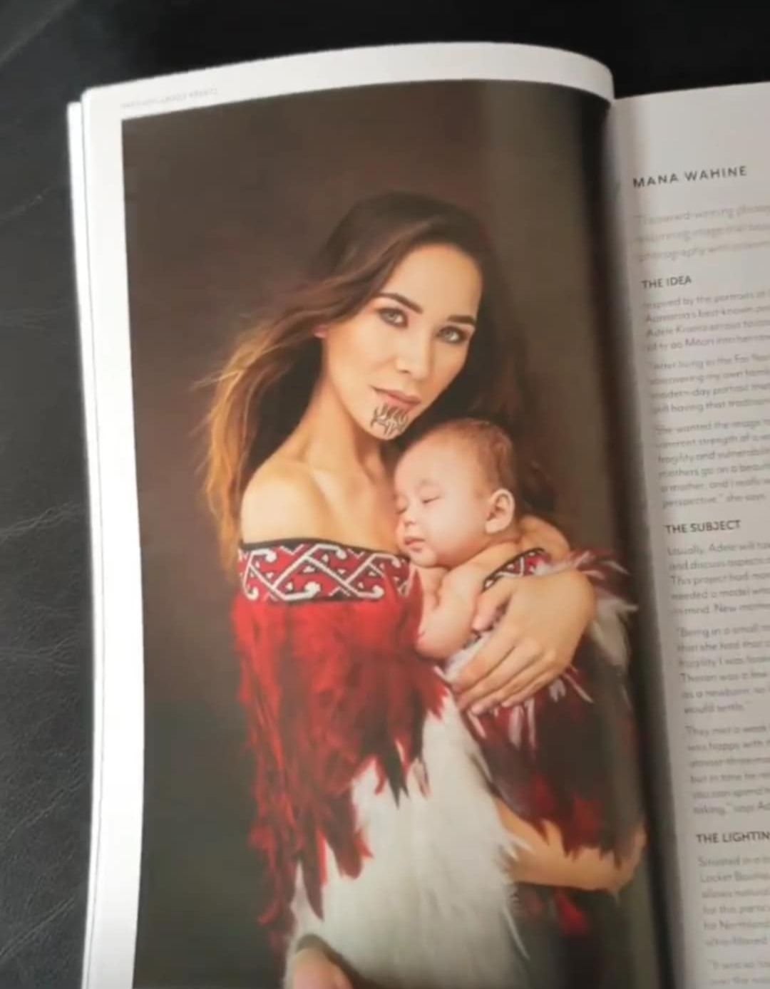A magazine page shows a mother in a red traditional dress holding a sleeping baby against a dark background.