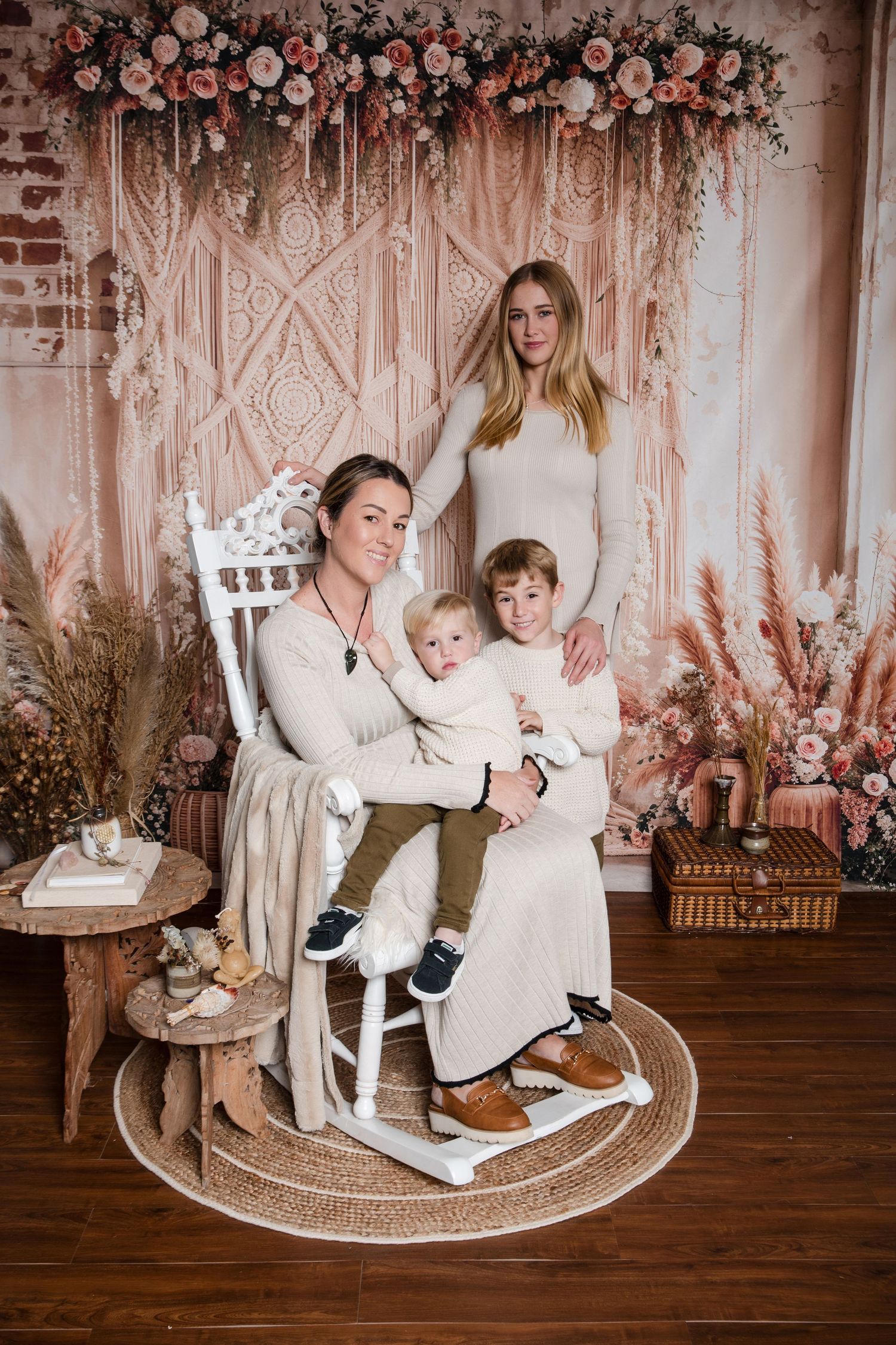 Vintage family portrait with macrame backdrop, floral arrangements and decorative elements in a warm boho setting.