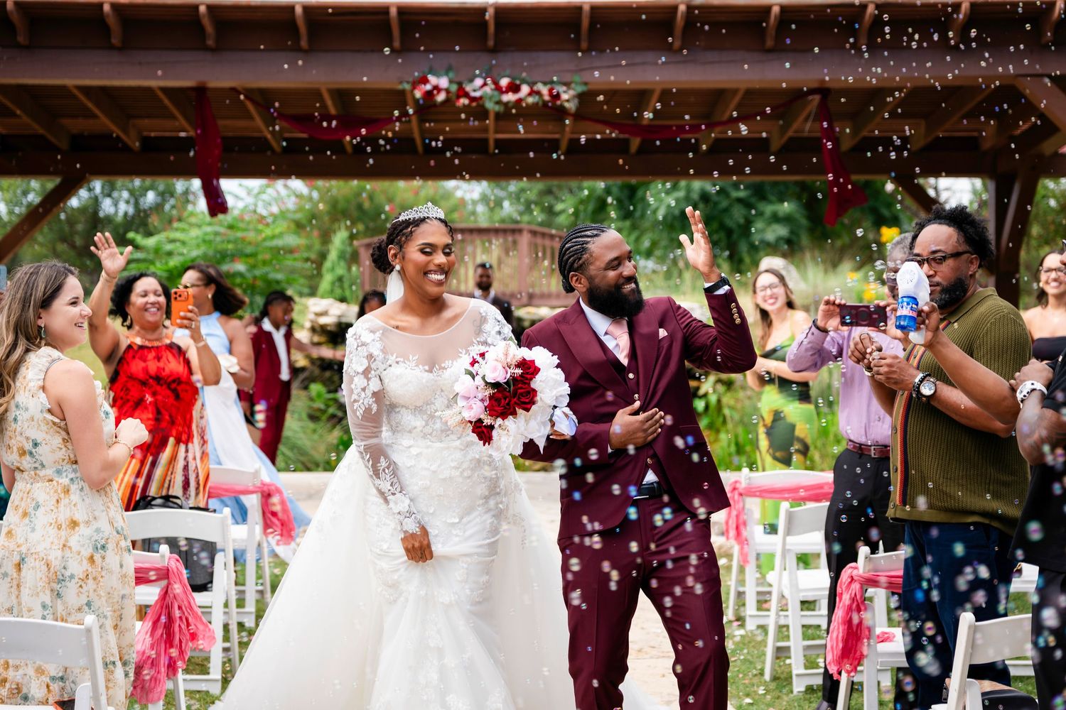 Joyful newlyweds walk down the aisle as guests shower them with colorful confetti at an outdoor wedding ceremony.