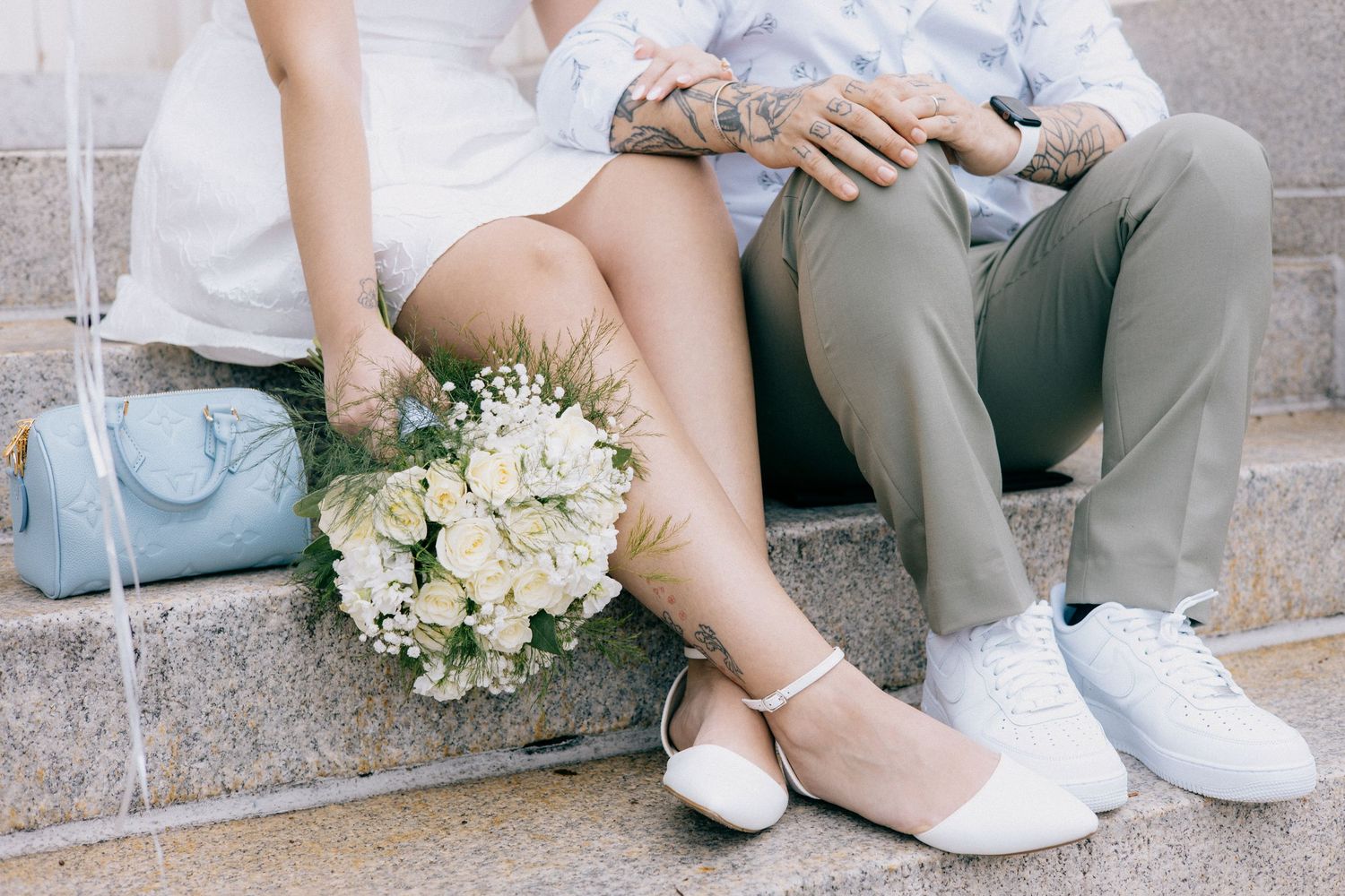 Wedding couple sitting together with white floral bouquet and formal attire.