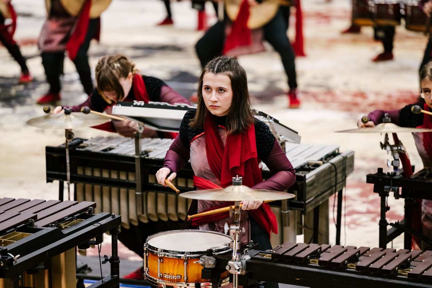 Percussion performers play marimbas and drums during an indoor show.