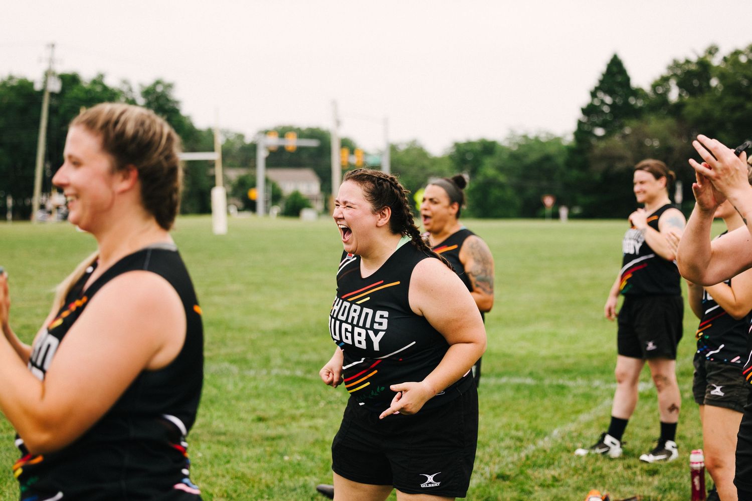 A group of athletes celebrating together on a green sports field during a sunny day.