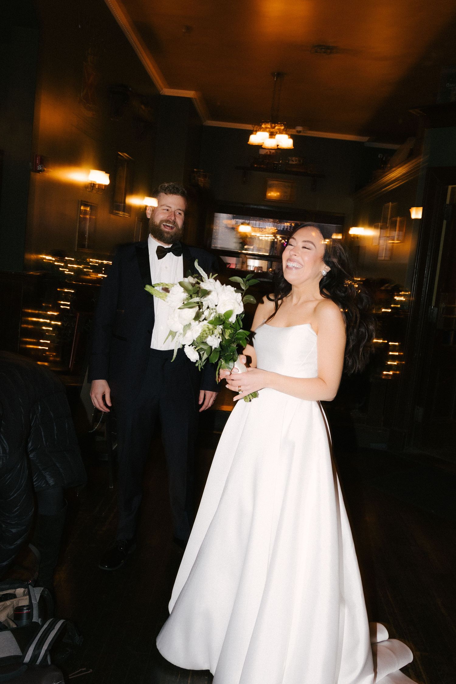 A couple shares a joyful dance moment together at their wedding reception in a dimly lit venue.