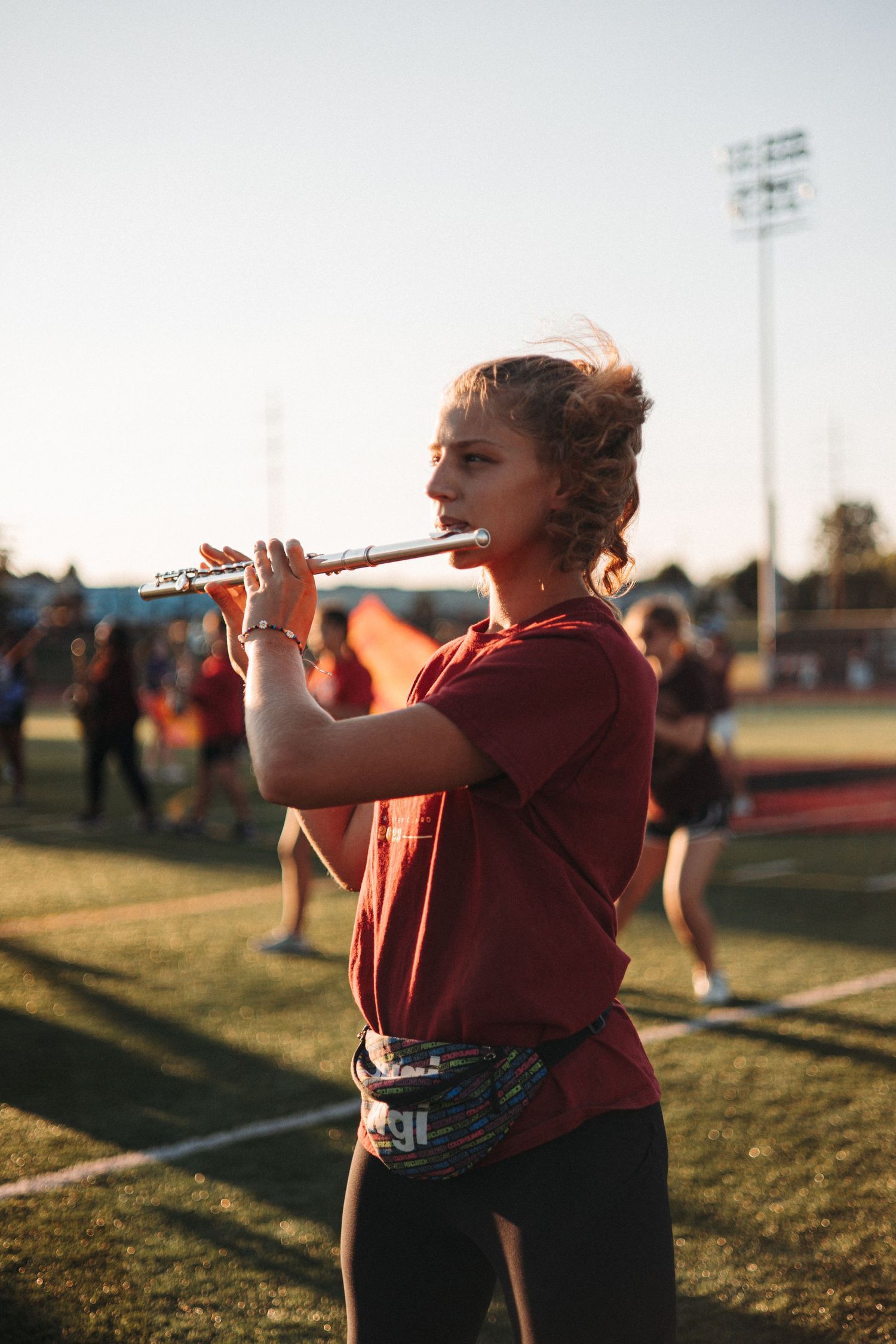 Color guard member practicing with equipment on a field at golden hour.