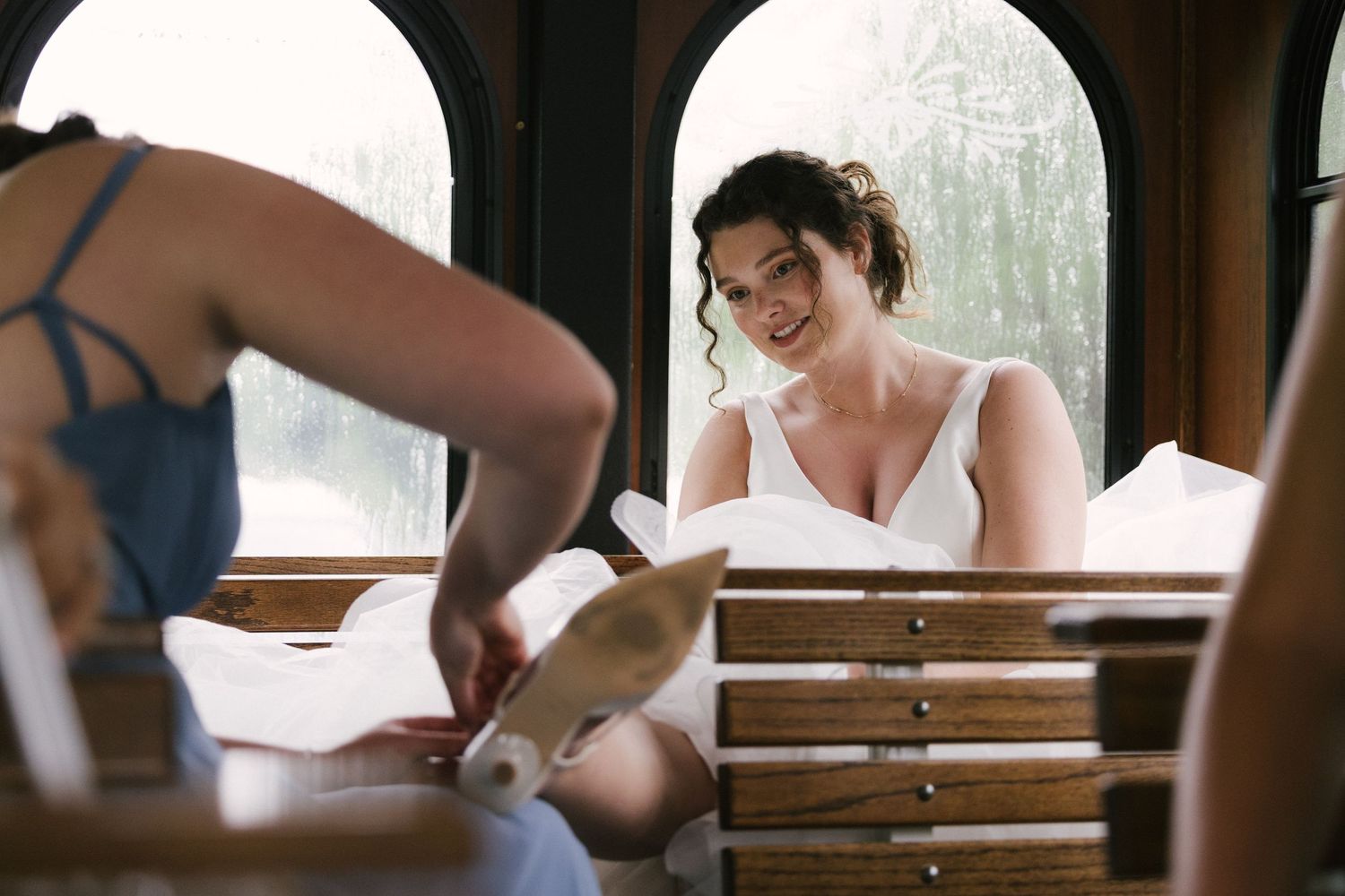 A series of candid wedding preparation moments showing details of dress fitting and styling in a sunlit room.