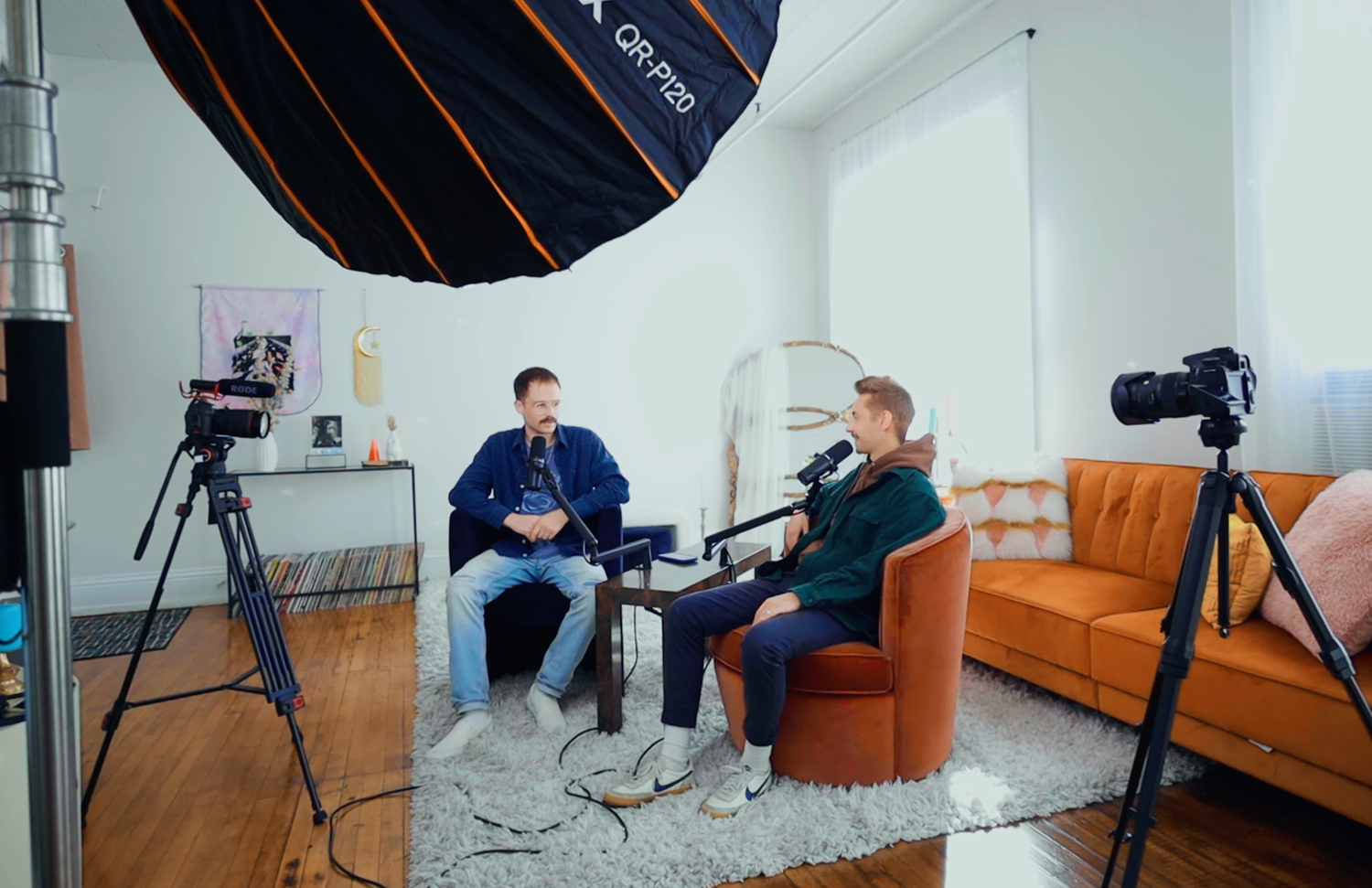 Professional photo studio setup with lighting equipment and orange furniture.