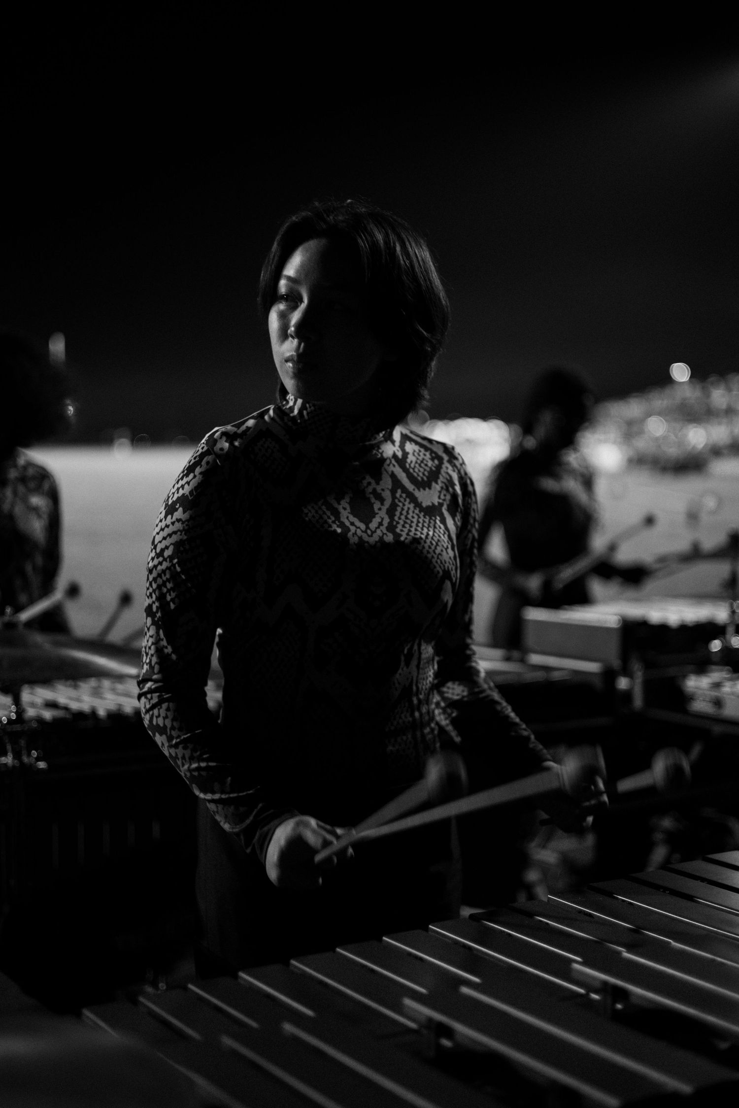 Musicians perform on xylophones during a dark outdoor performance.