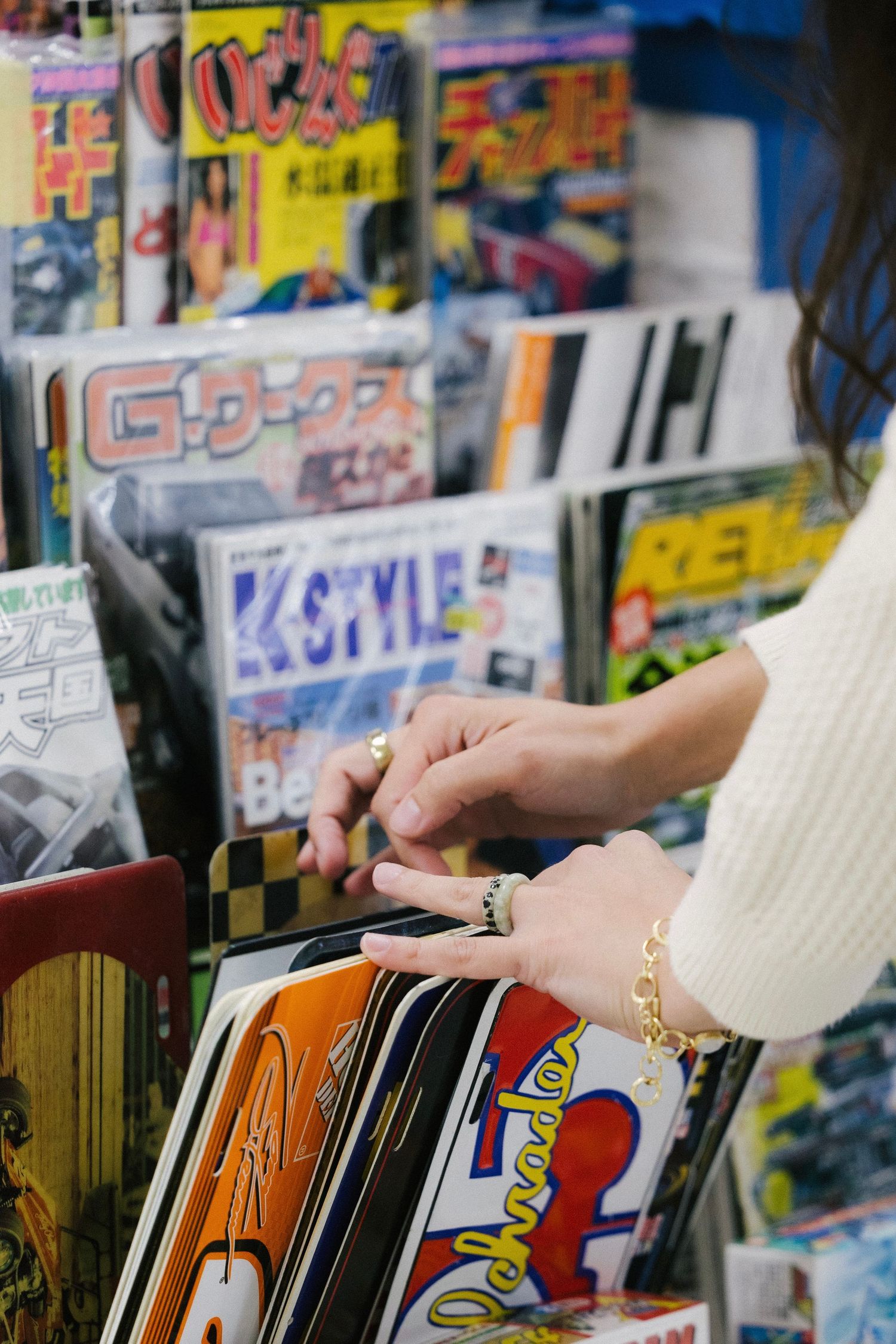 Hands browsing through colorful comic books and magazines displayed in retail store racks.