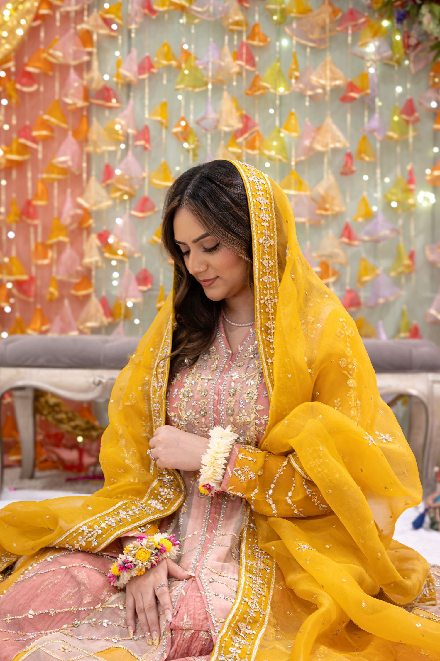 Traditional South Asian attire featuring a pink embroidered dress paired with a vibrant yellow dupatta against decorative backdrop.