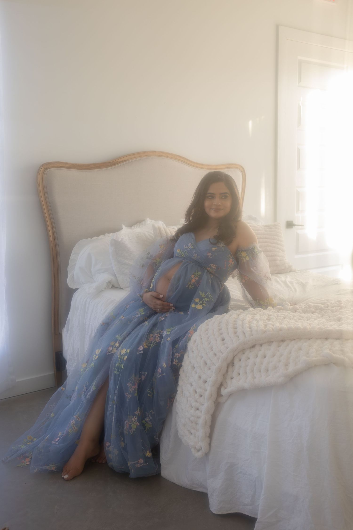 A dreamy photo series shows a figure in a blue dress reclining on a white chaise lounge in soft natural light.