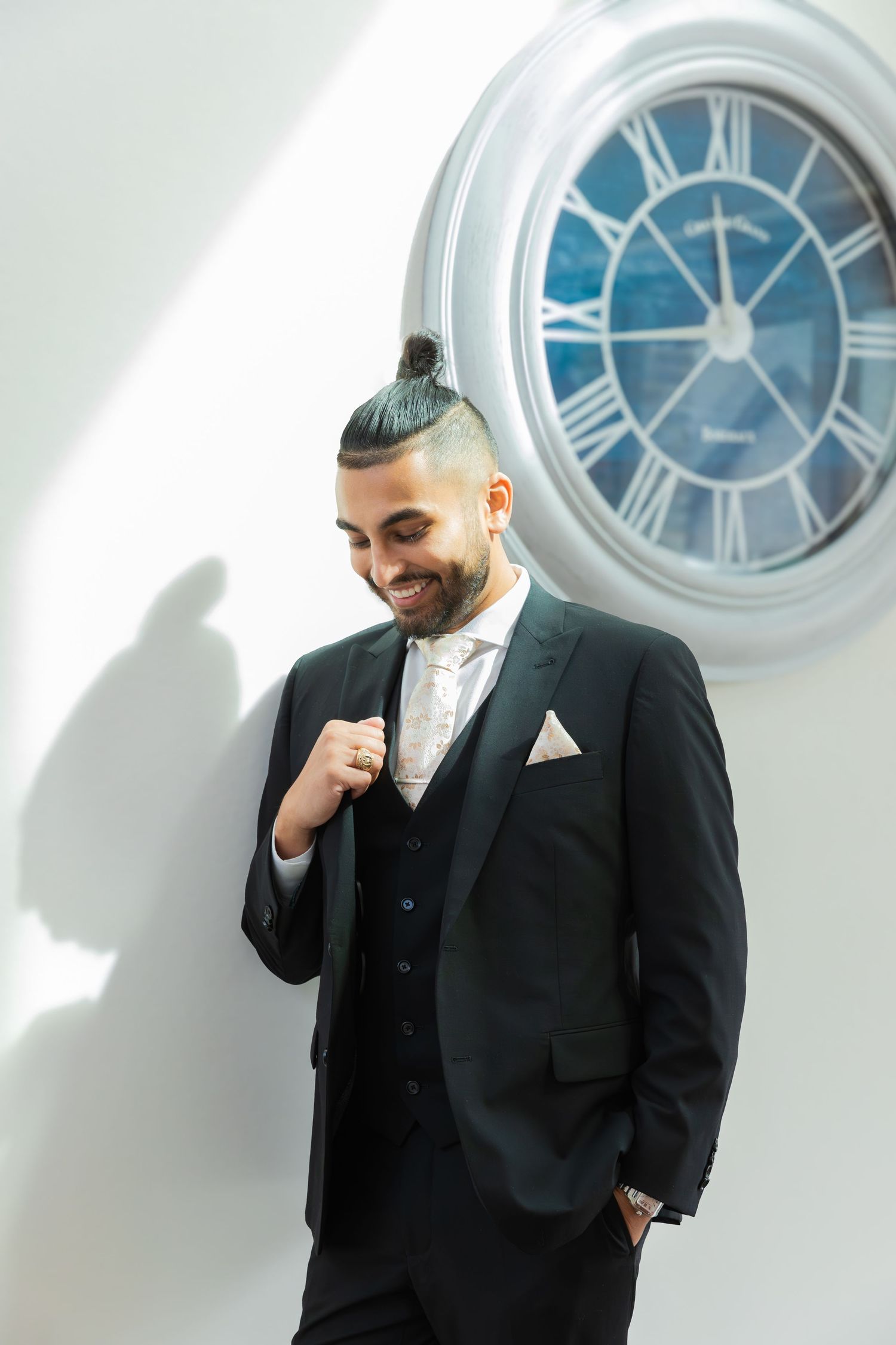 Formal portraits near a round window showing elegant black suit styling.