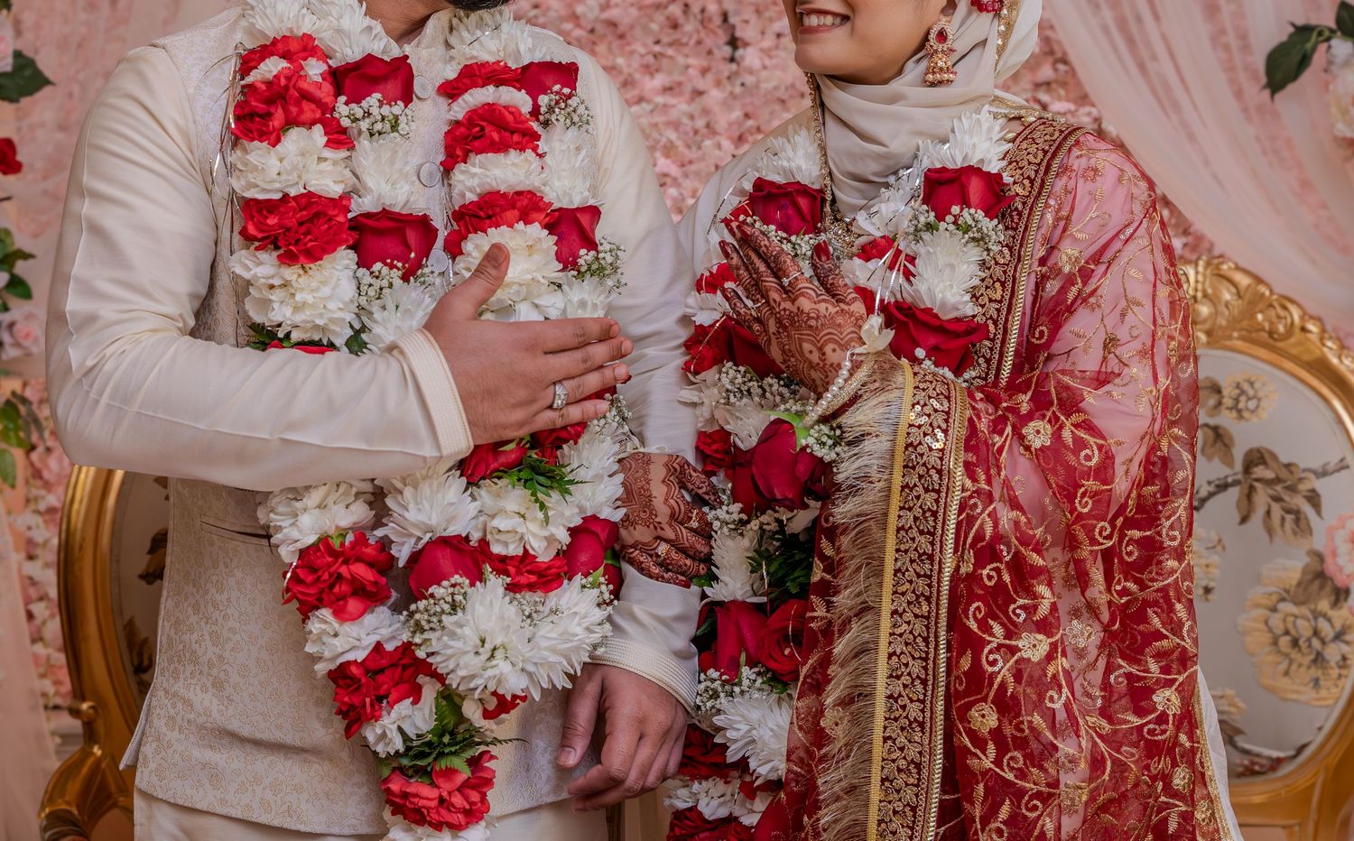Traditional South Asian wedding ceremony with red and white floral garlands and ornate attire.