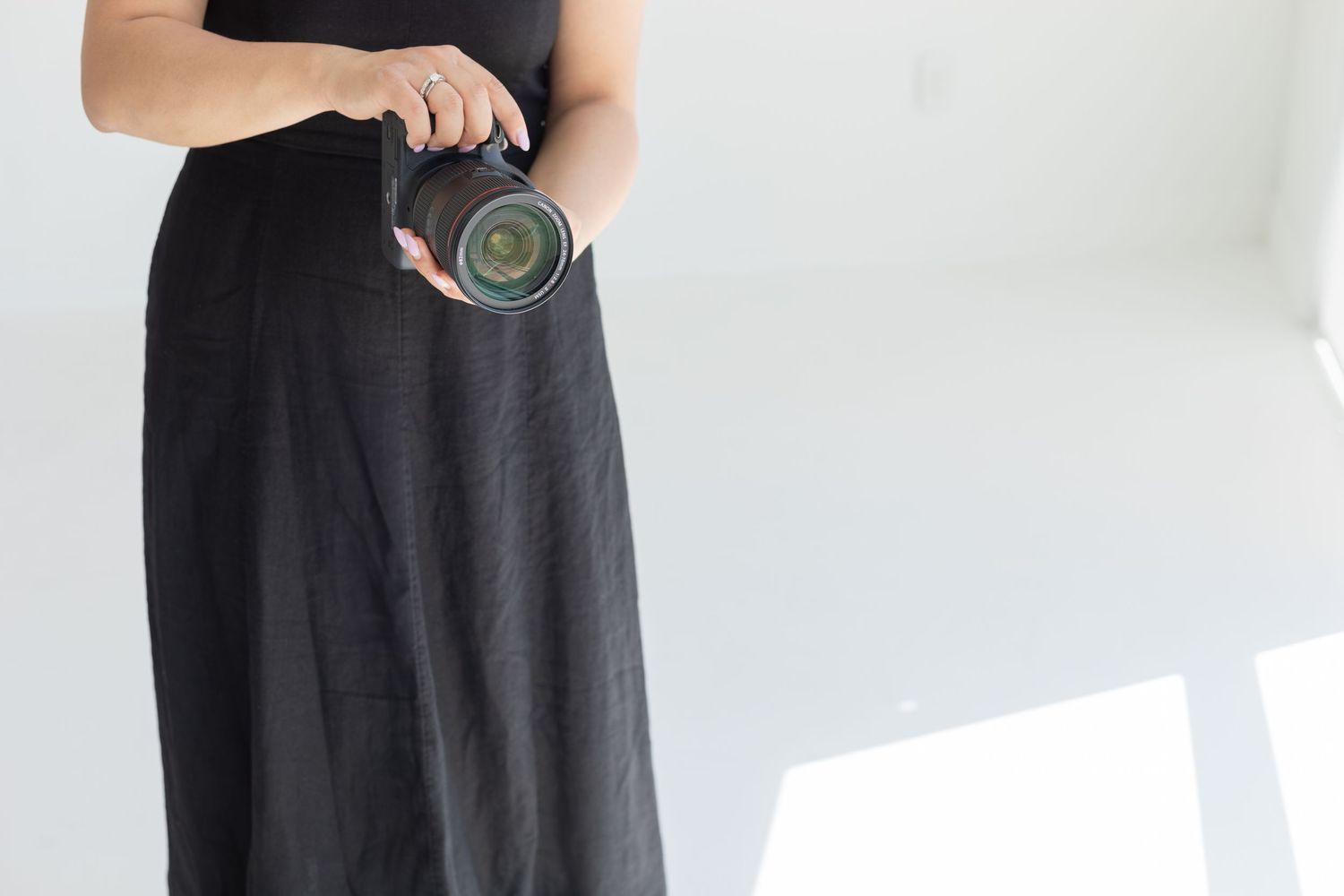 Close-up of hands holding camera lens against white background.