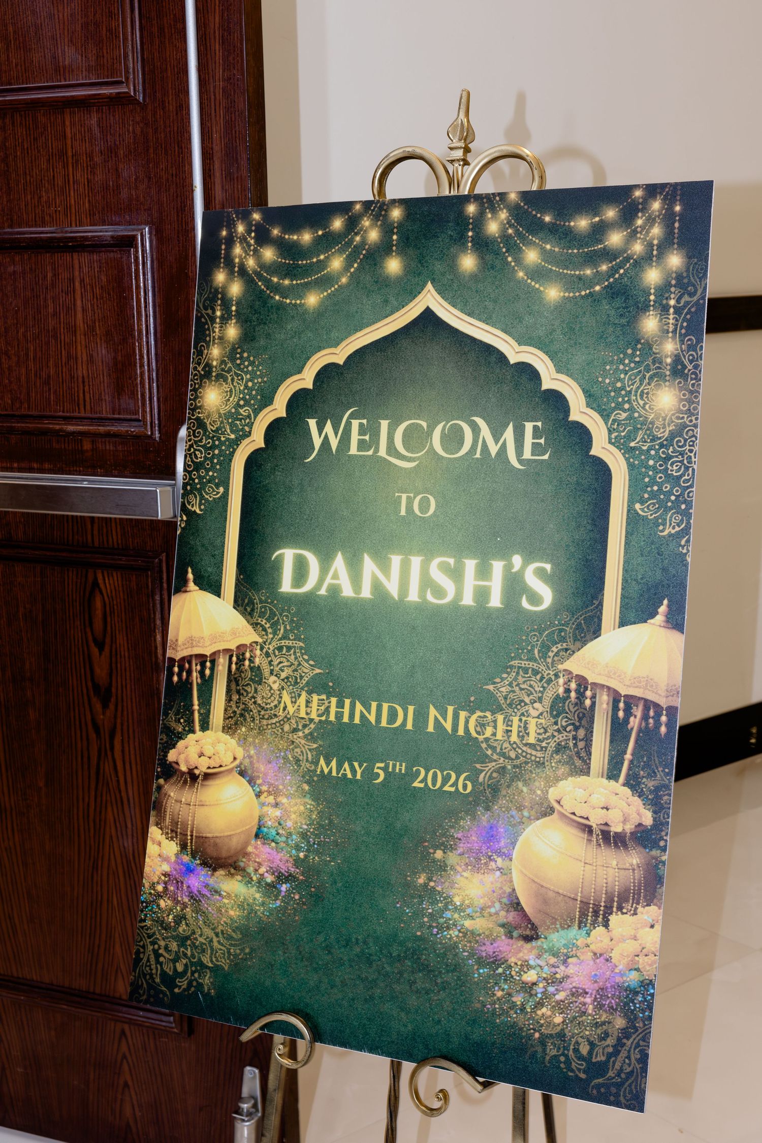 Elegant green and gold welcome sign for Danish's Mehndi Night on May 5th, 2026, decorated with fairy lights and floral motifs.
