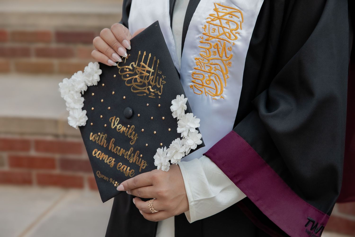 A decorated graduation cap with gold text and decorative elements against a black gown.