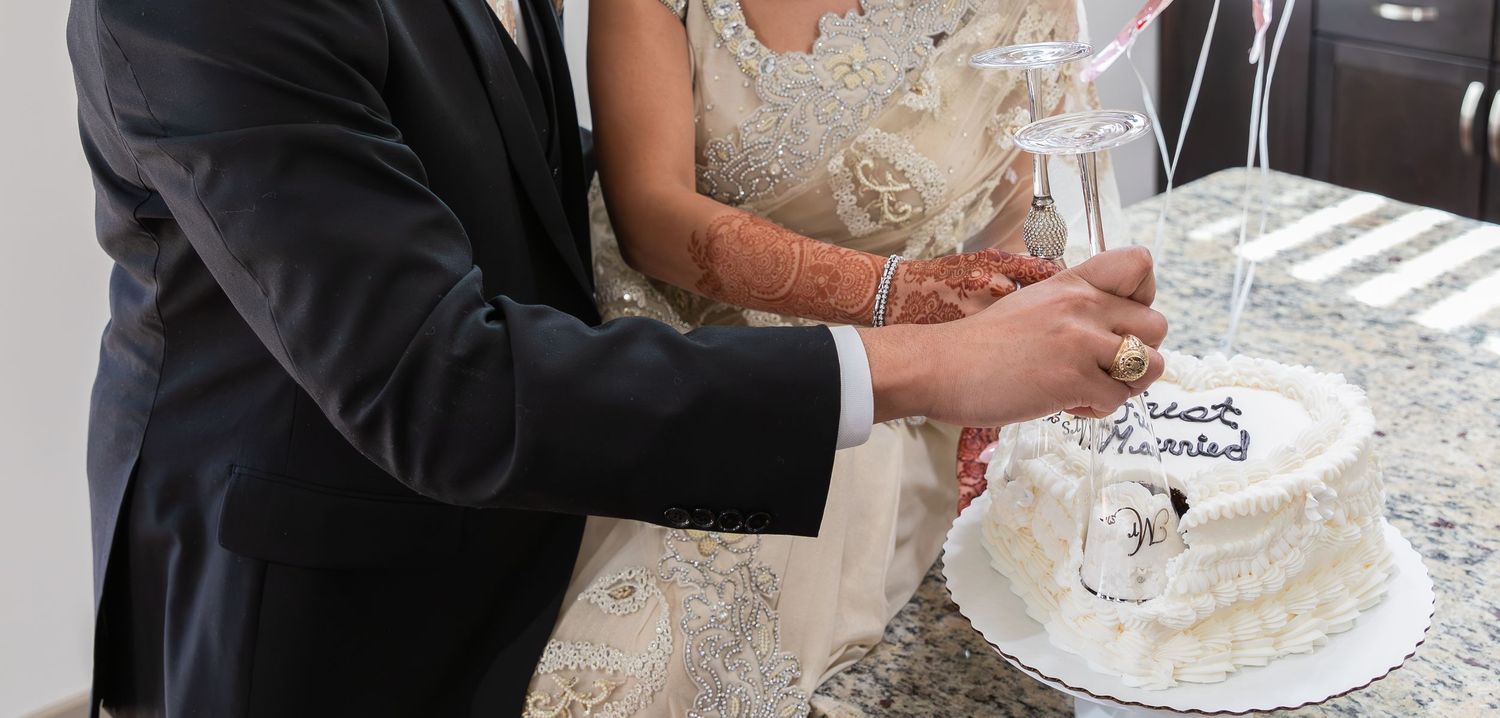 Newlywed couple cutting their white wedding cake together during reception.