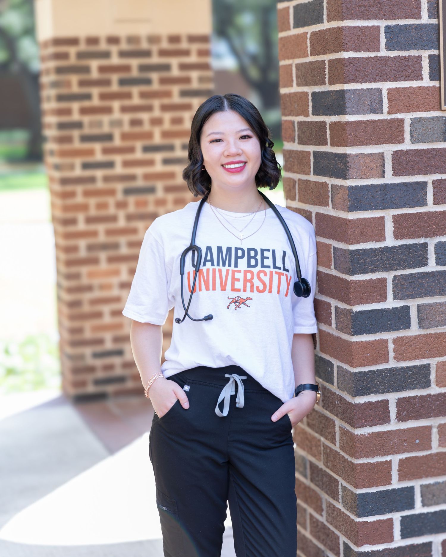 A collage of four photos showing someone wearing a Campbell University t-shirt and black pants against a brick wall.