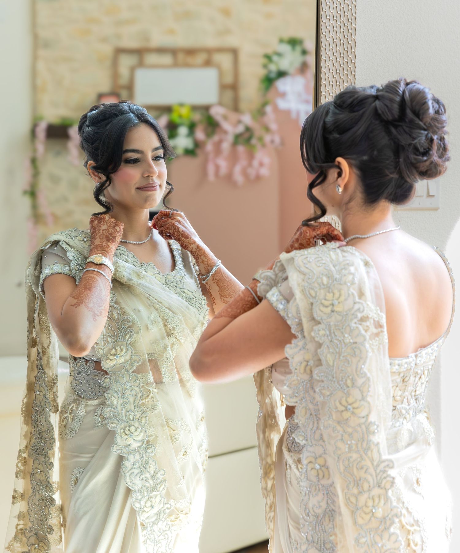 Final touches being made to traditional wedding attire in elegant dressing room setting.