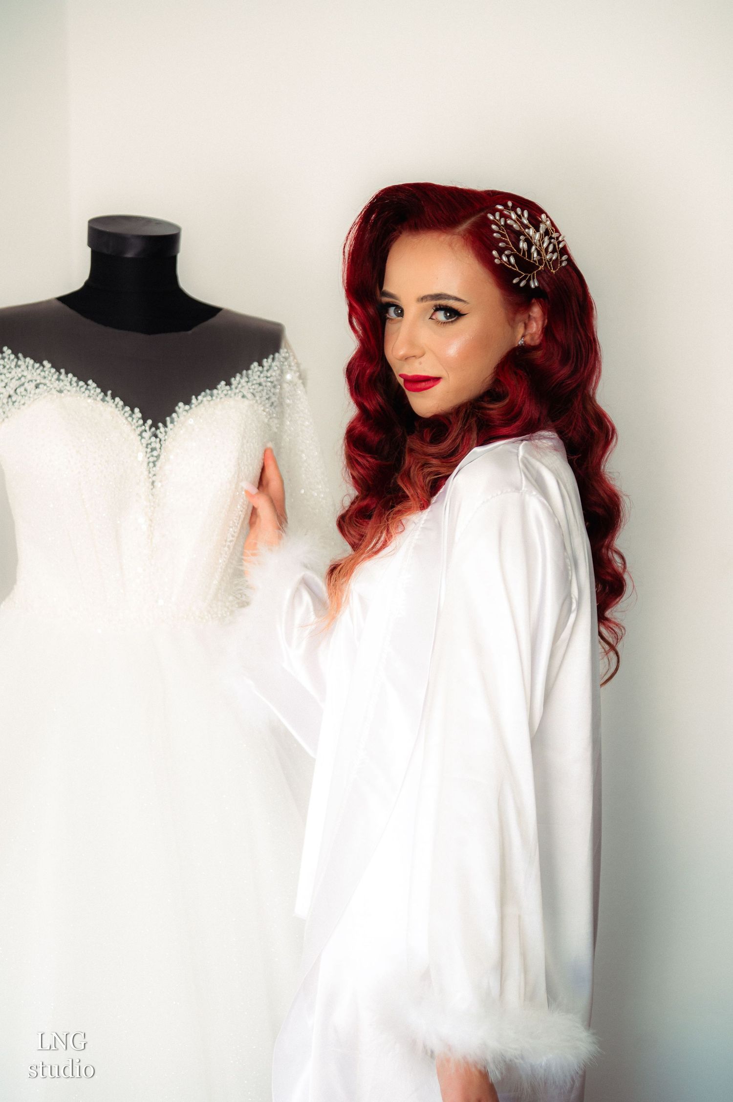 Elegant bridal preparation photo with wedding dress on mannequin and white robe.