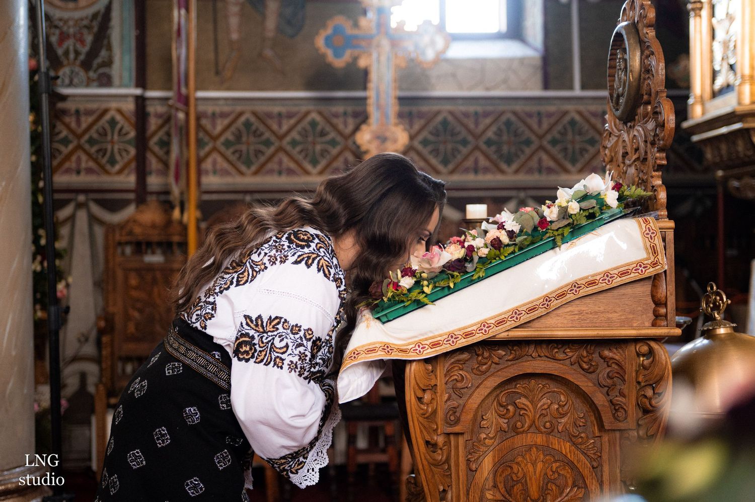 Woman bowing at decorated Orthodox altar during religious ceremony.