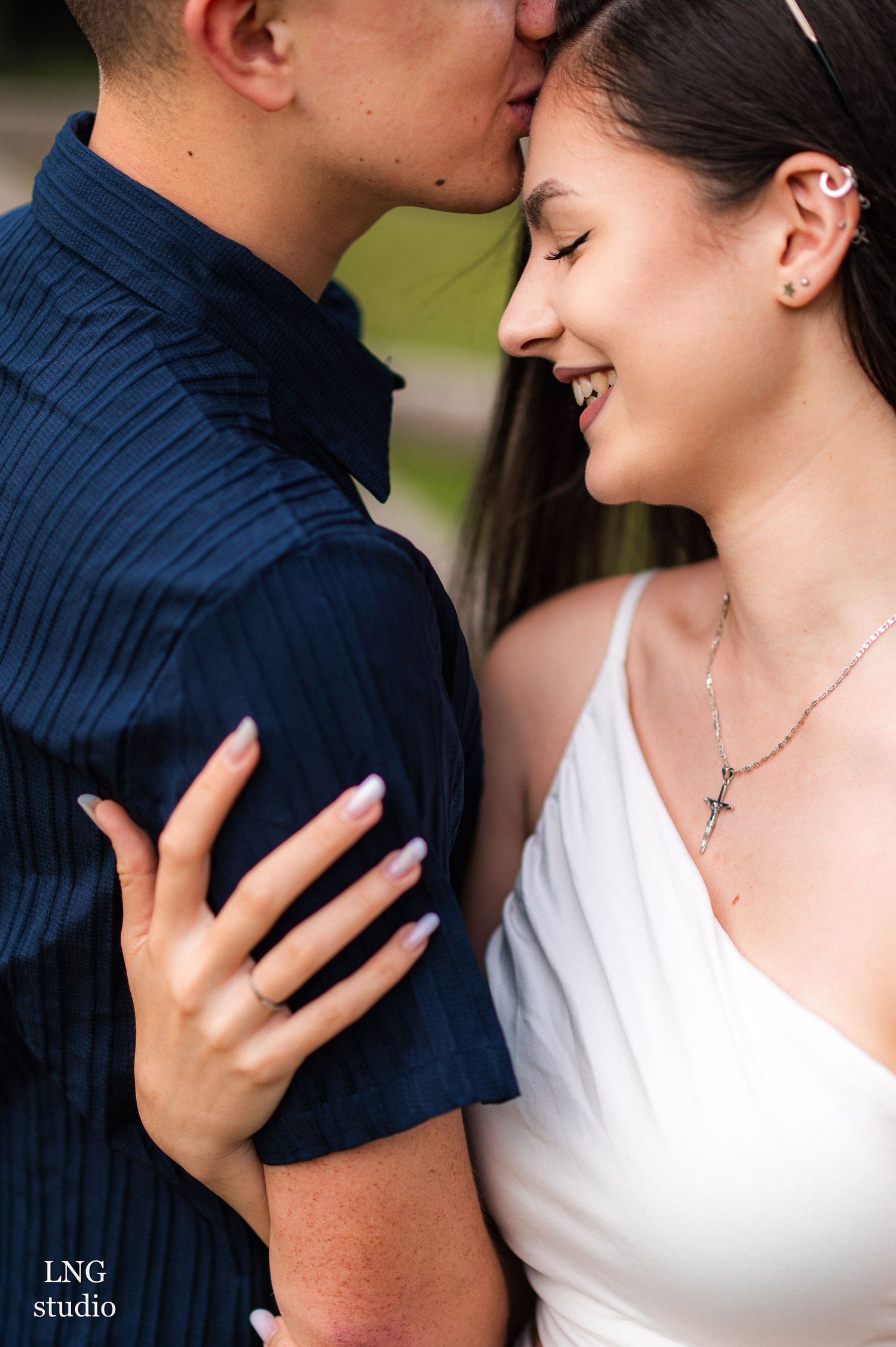 Close-up of tender moment between couple in navy and white attire.