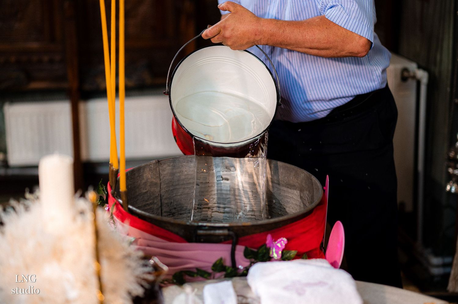 Person pouring liquid into a ceremonial basin during a religious ritual.