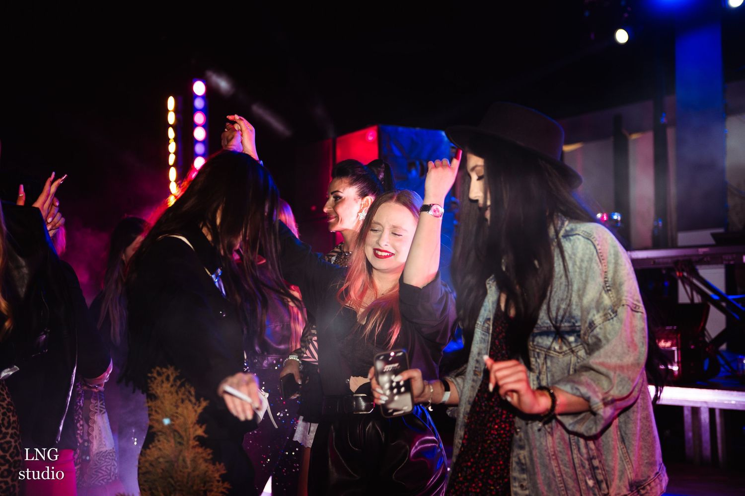 Party scene with people dancing under colorful nightclub lighting.
