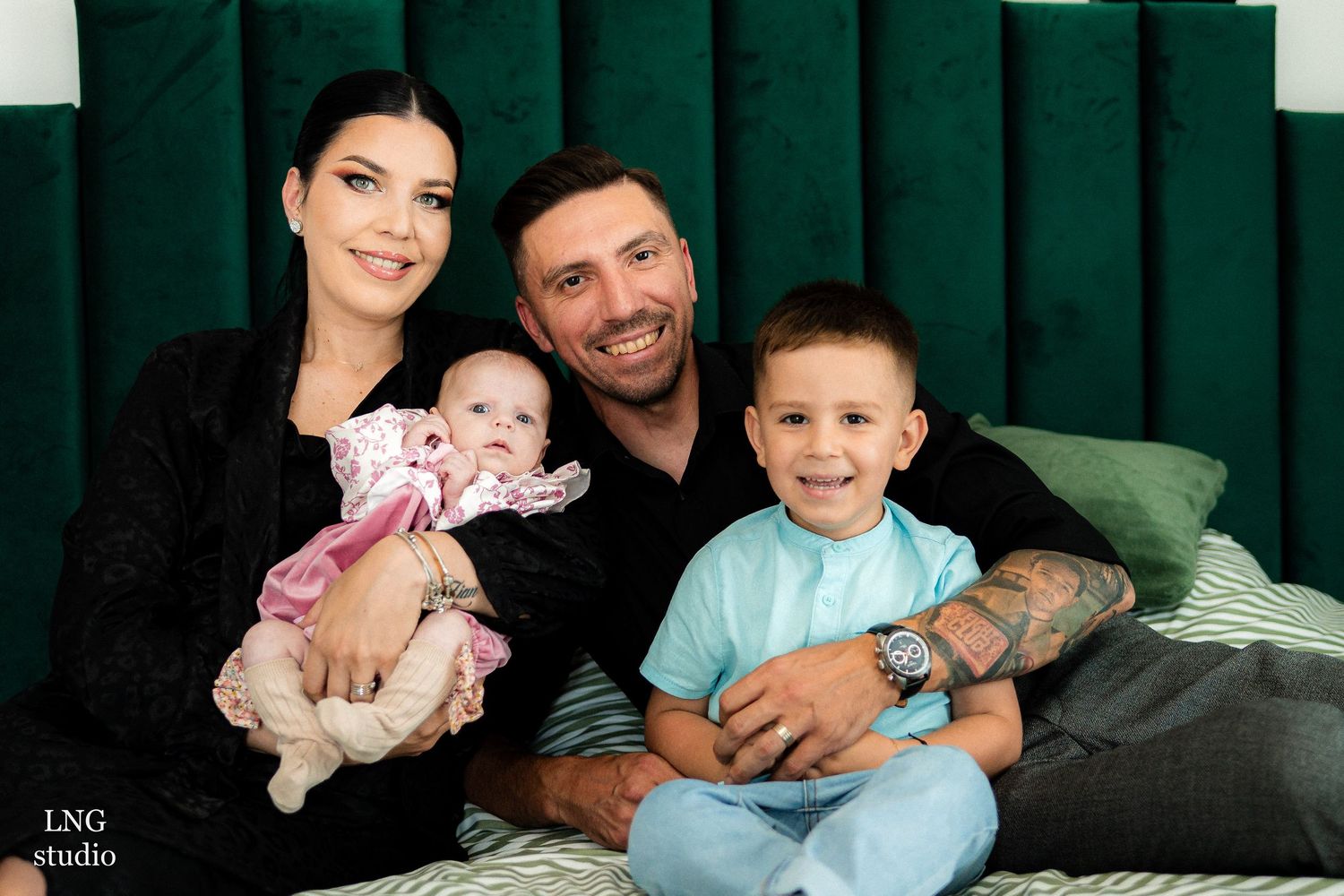 Family portrait with green velvet backdrop and coordinated outfits.