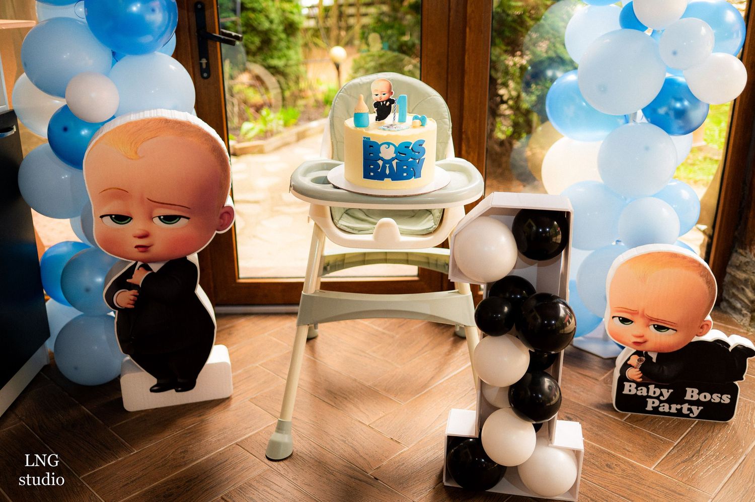 Boss Baby themed birthday party setup with balloon arch and cardboard cutouts.