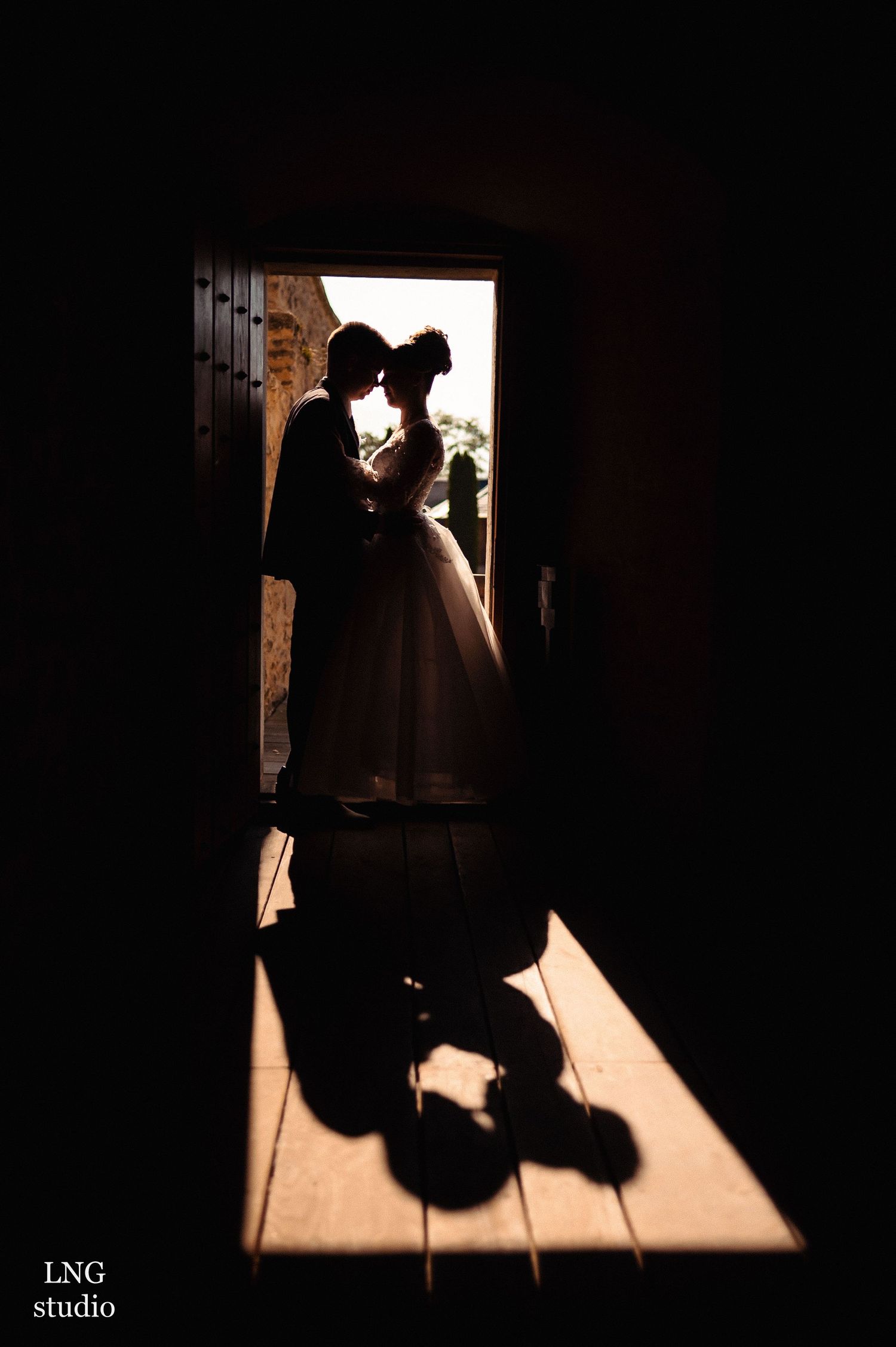 Silhouetted couple standing in doorway creating dramatic shadow on floor.