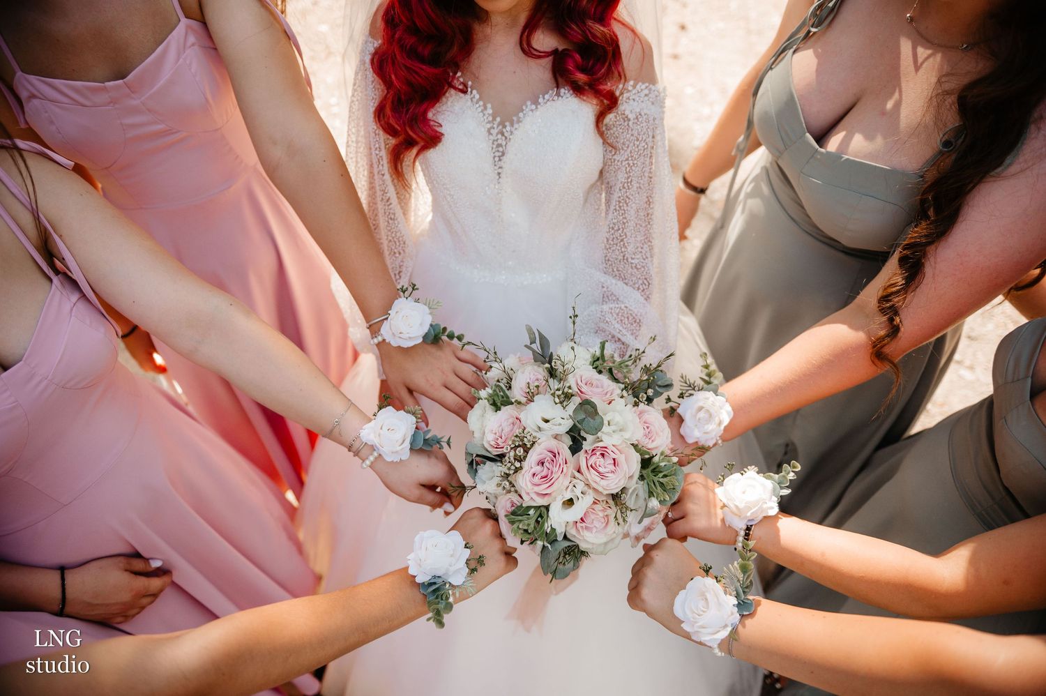 Wedding party members hold a white bridal gown train in a flowing arrangement.