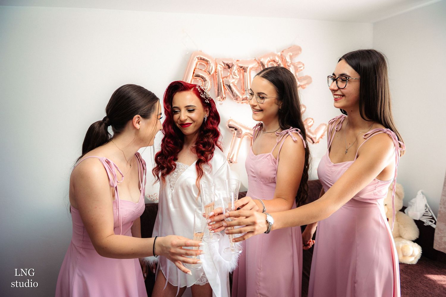 Emotional pre-wedding moment shared between bride and bridesmaids in pink dresses.