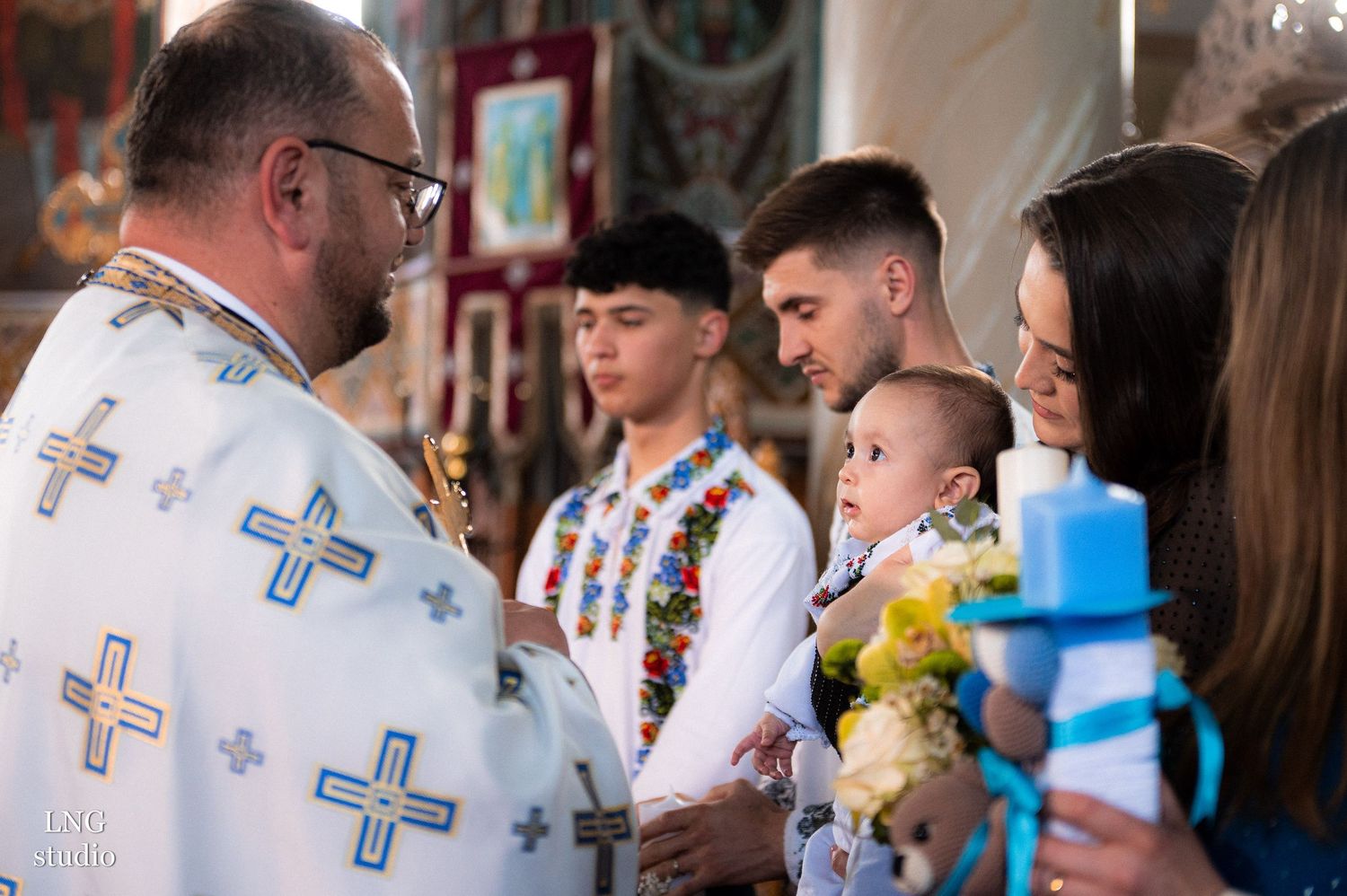 Orthodox priest in ceremonial robes conducts religious ceremony in decorated church.
