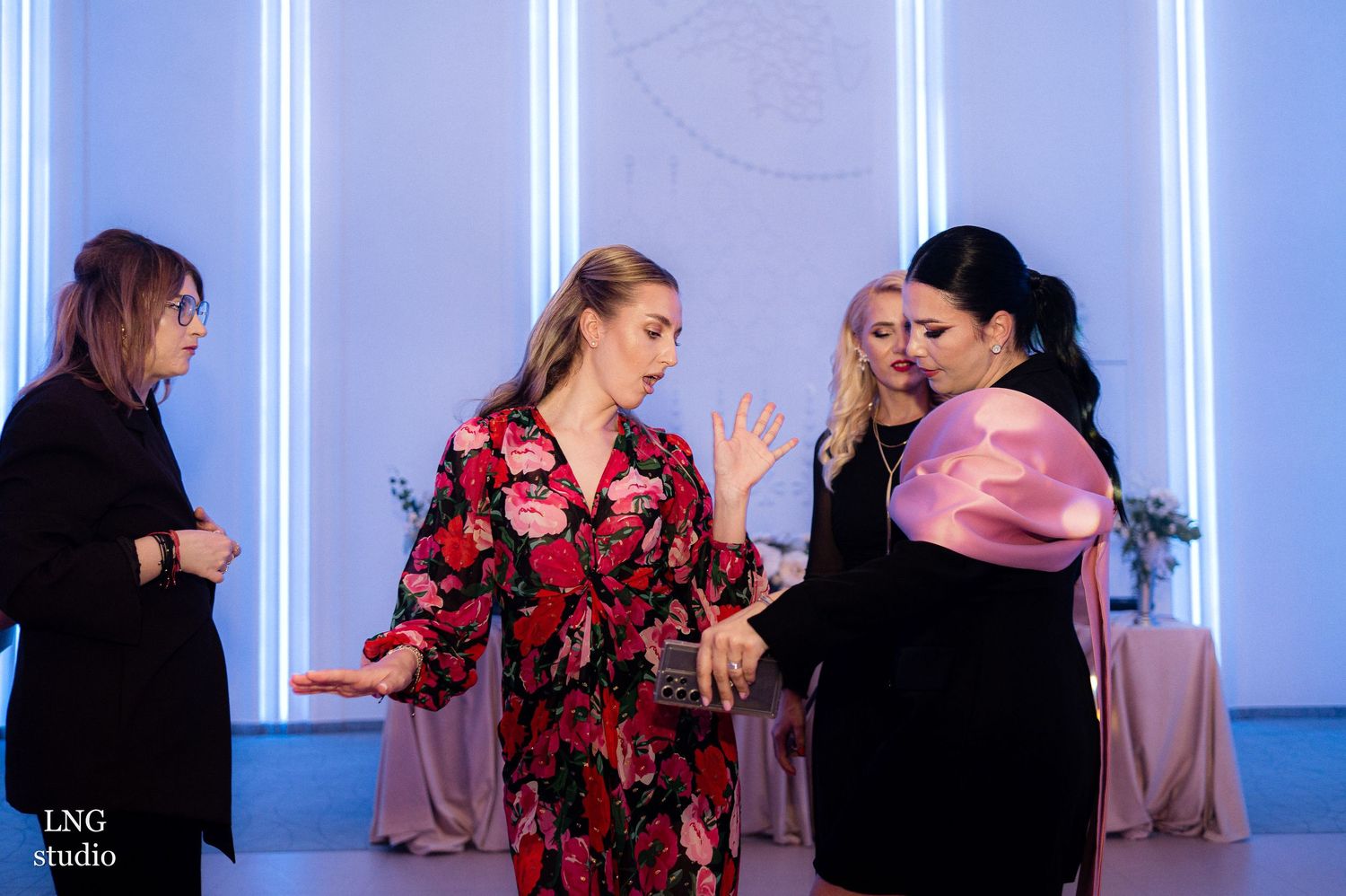 Party guests mingling in an elegant venue with blue illuminated pillars.