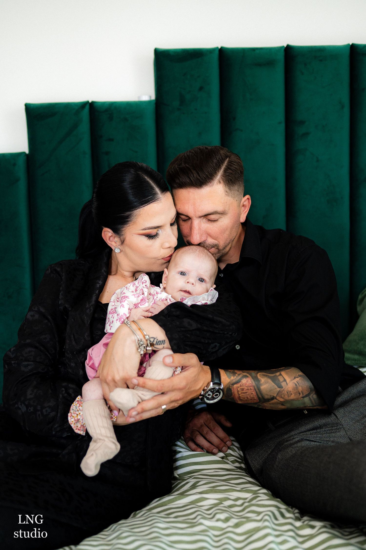 Intimate family moment captured against emerald green velvet backdrop.
