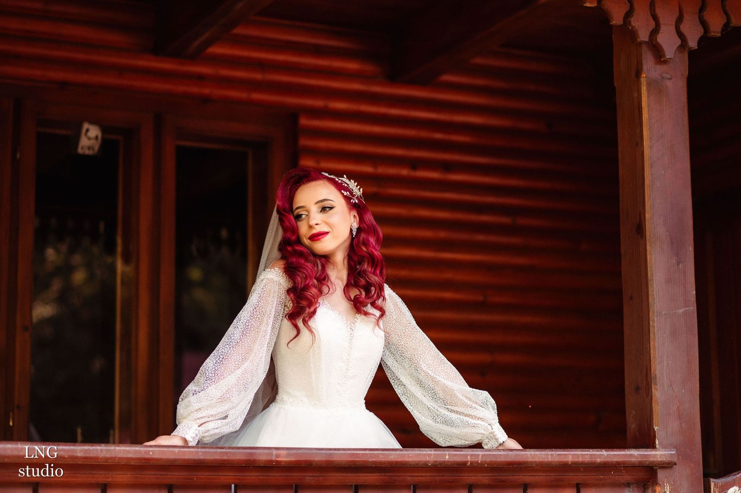 Bride in white dress poses in rustic wooden setting with dramatic lighting.