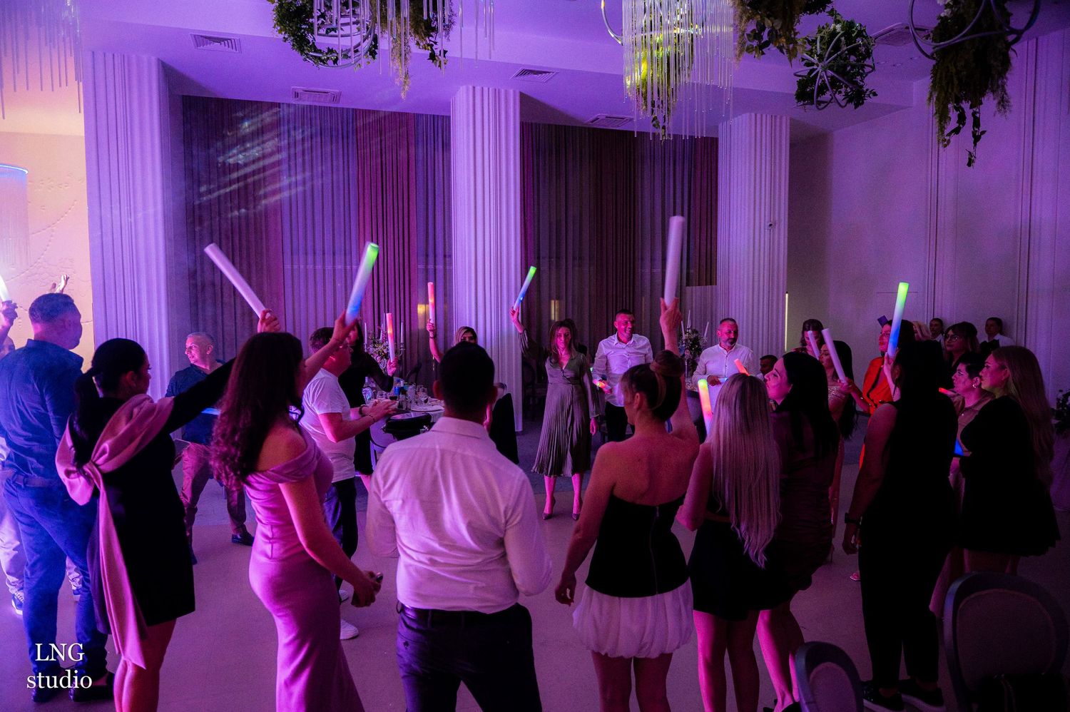Wide shot of an elegant ballroom with purple uplighting and dancing guests.