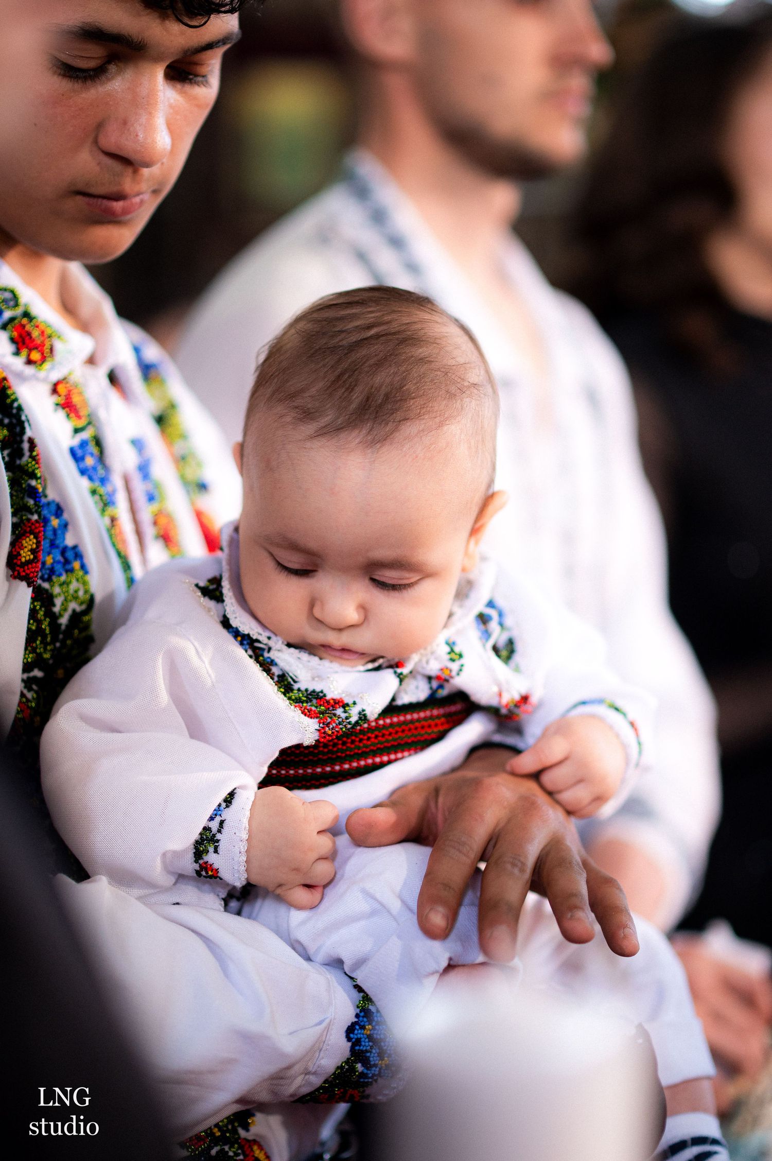 Baby in traditional white embroidered christening gown during ceremony.