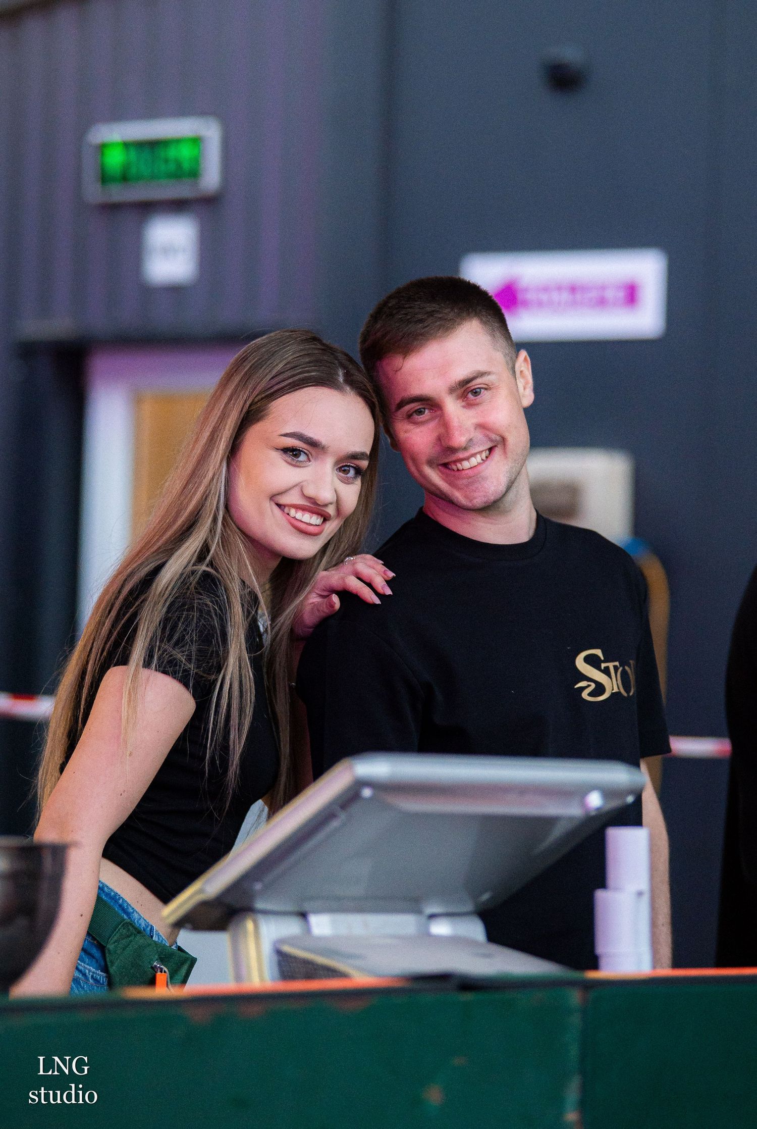 Team members interact playfully while working behind a modern bar counter.