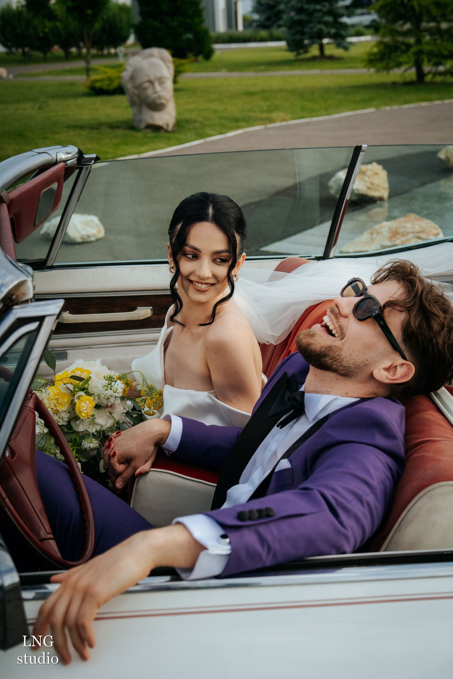 A romantic couple sharing intimate moments in a classic car with yellow flowers visible.