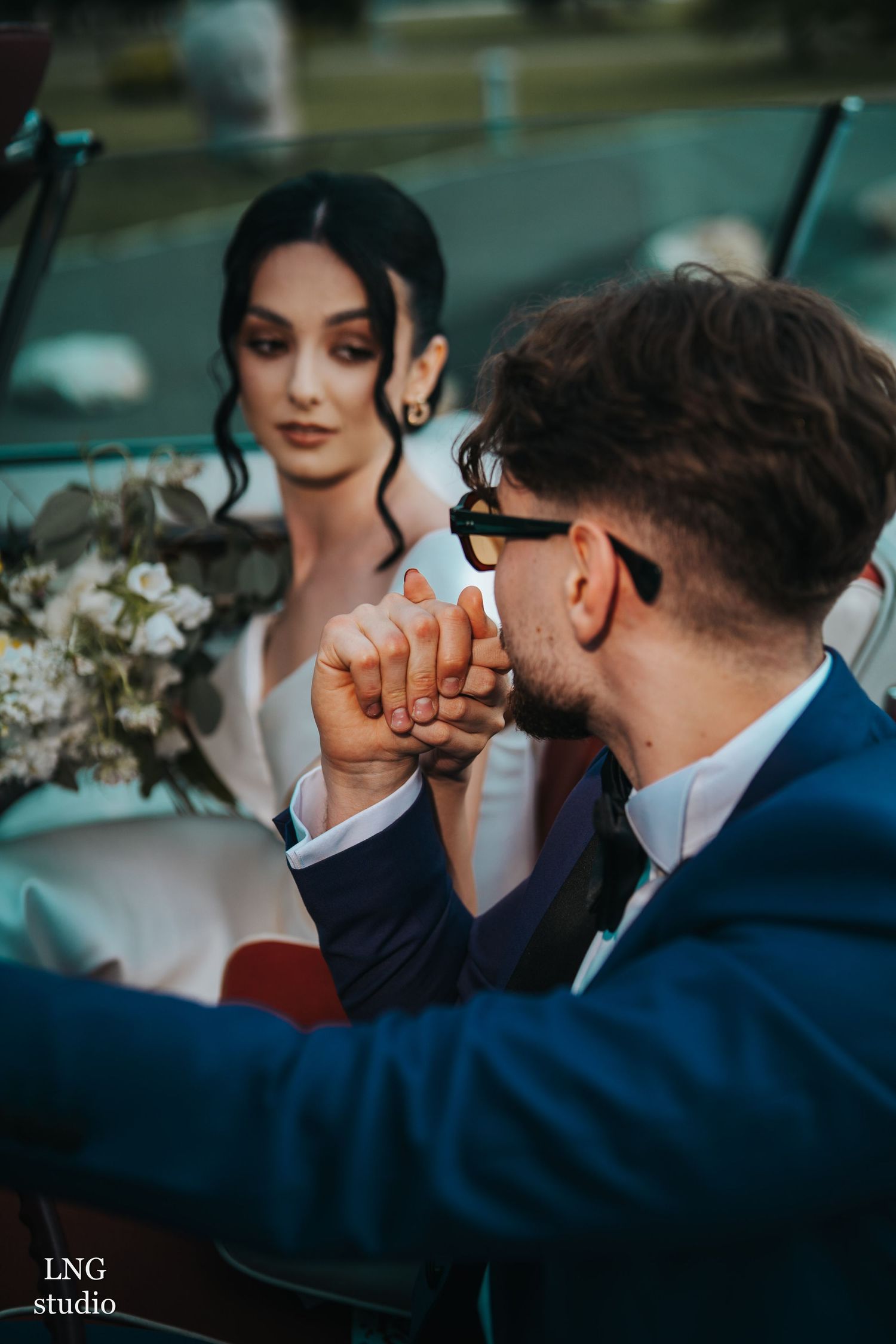 Wedding party in blue suits and formal attire gathered in an intimate moment outdoors.